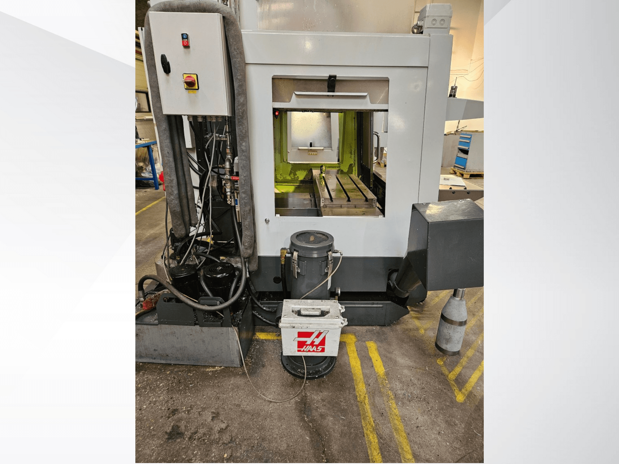 Haas CNC machine front view showcasing control panel, coolant tank, and machined bed on display.