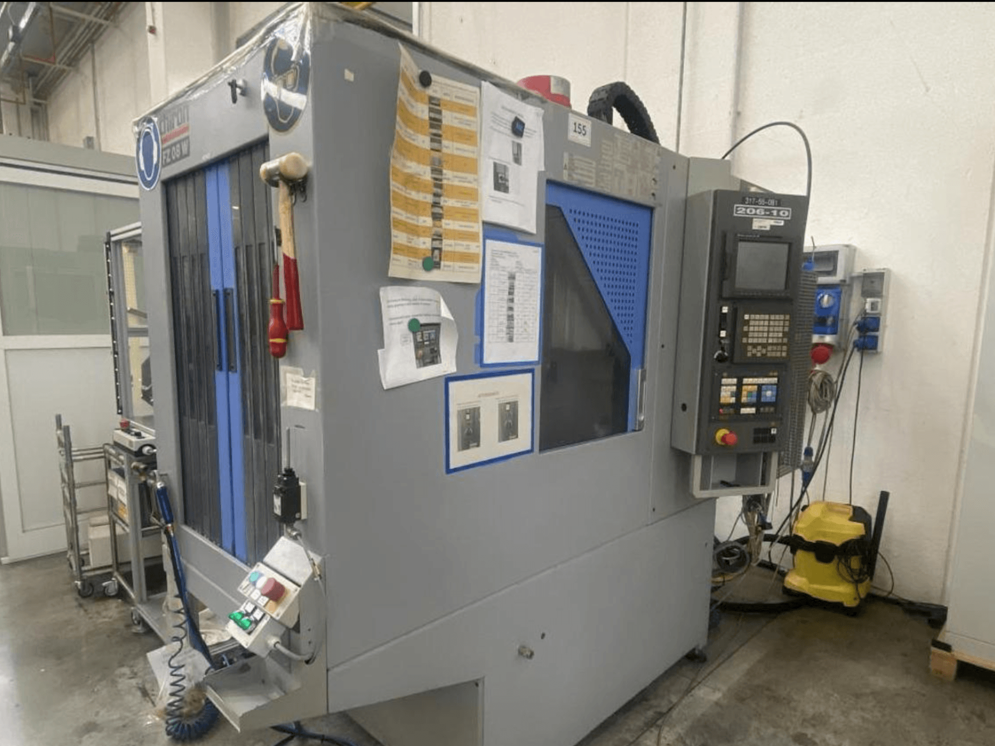 CNC machine by Shin Lin, front view, featuring control panel, operating buttons, and safety instructions attached.