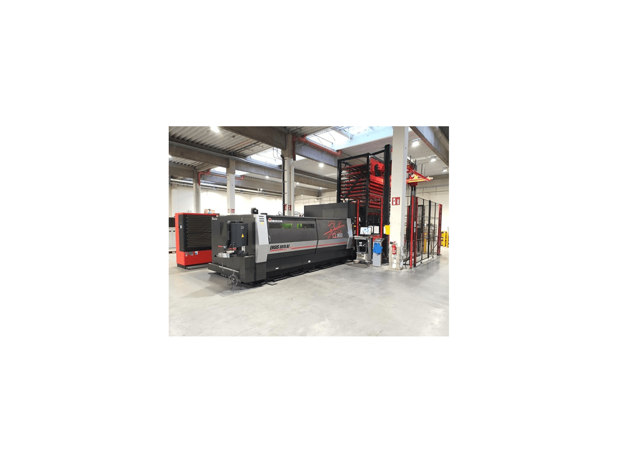 Amada ENSIS 3015 Aj laser cutting machine from a front view, set in a spacious industrial workshop with metal shelving.