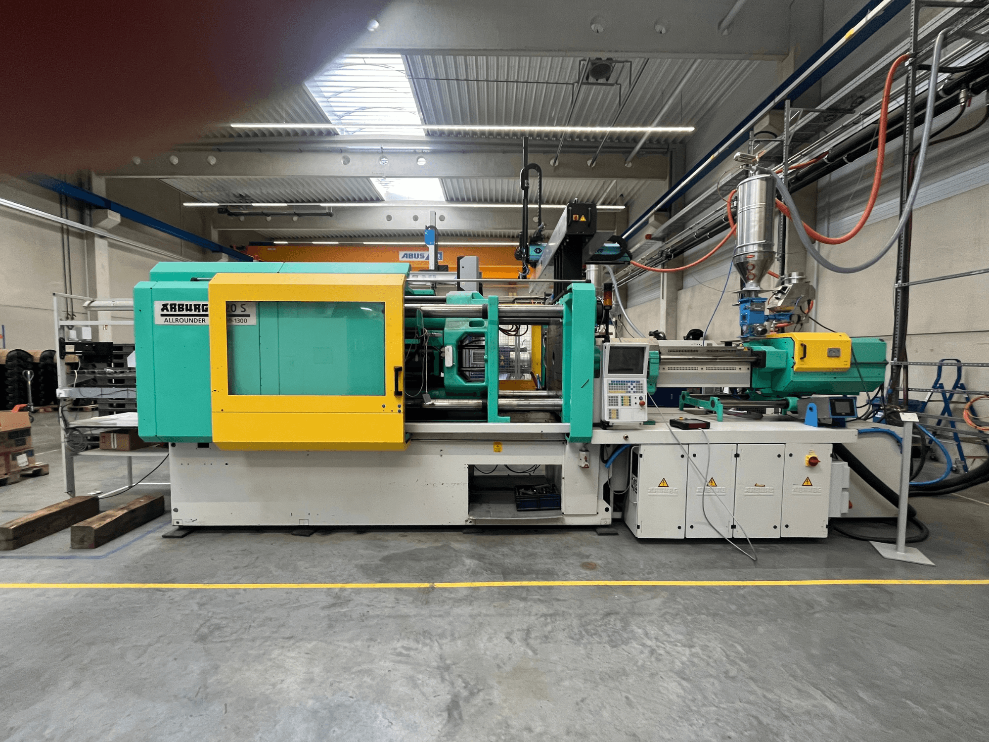 ARBURG Allrounder 370S plastic injection molding machine, side view, with green and yellow casing, control interface visible.
