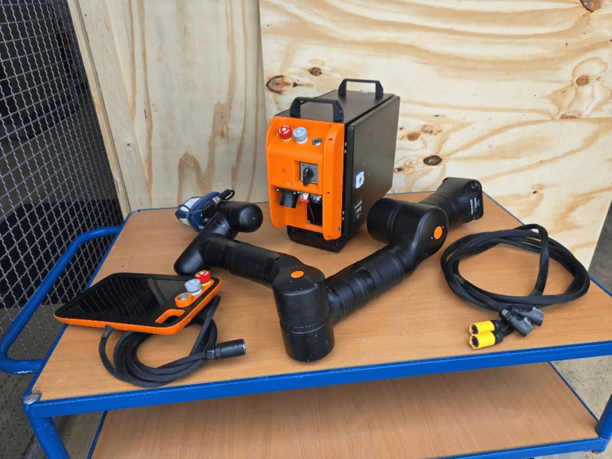 KASSOW ROBOTS KR810 collaborative robot, front view, includes controller, cables, and connectors on a wooden table.