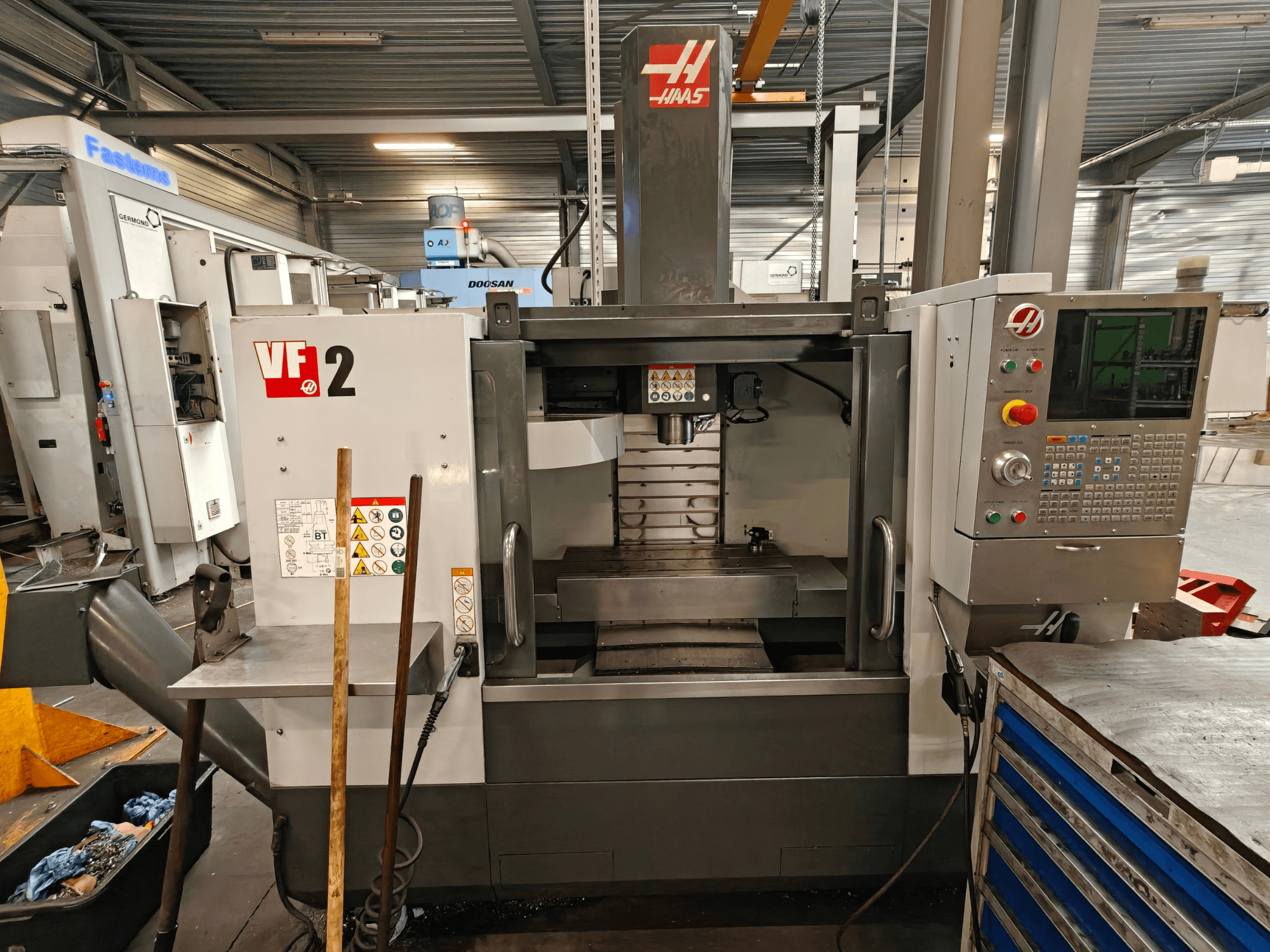 HAAS VF-2 Vertical Machining Centre, front view, showcasing controls, spindle, and work table in a workshop setting.