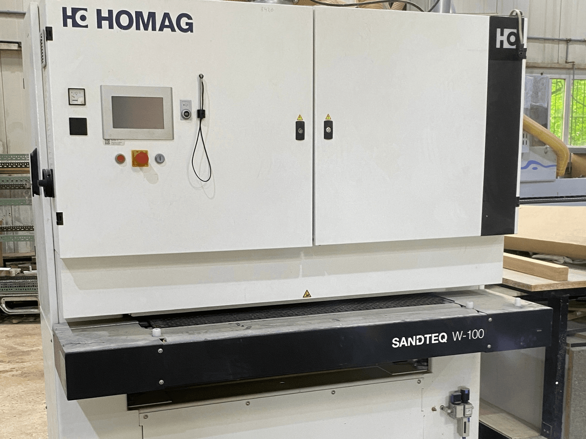 HOMAG SANDTEQ W-100 belt sander in a workshop, showcasing control panel, dust port, and sanding belt area. Front view.