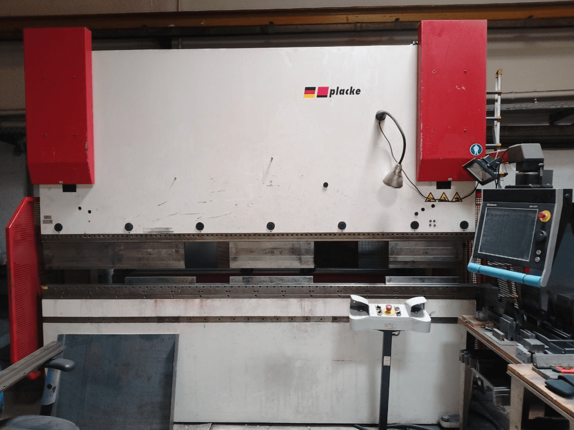Press brake PLACKE QPB-4 150/3100, front view showing control panel, red arms, and metal bending area.