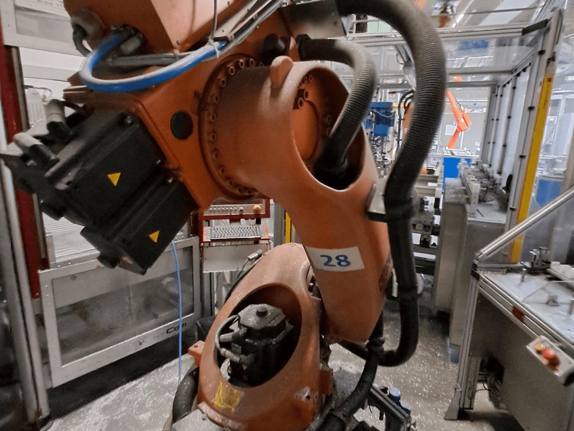 KUKA KR30-3 robot arm close-up, featuring orange body, labeled with number 28, showing motors and wiring from a side view.