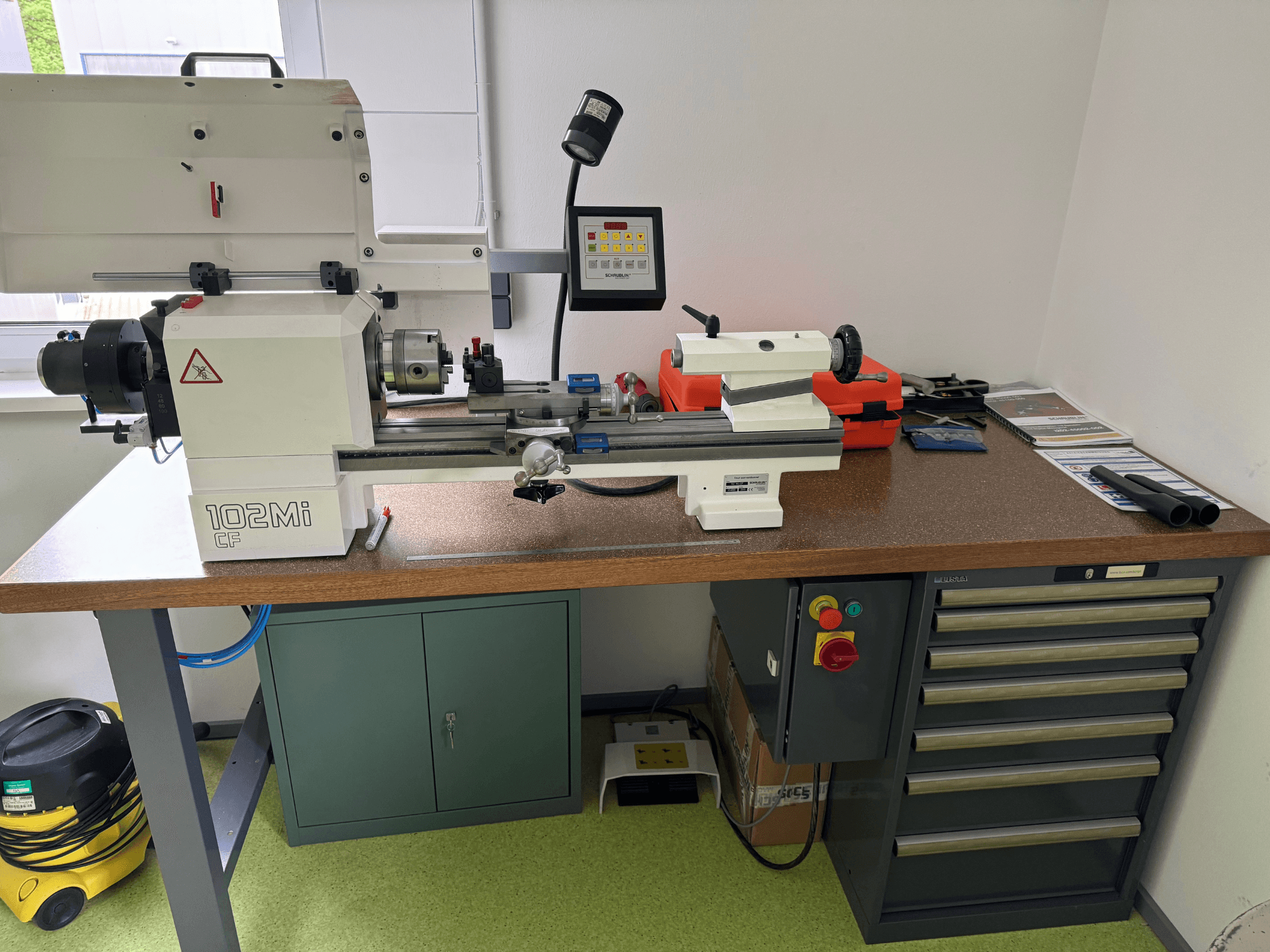 SCHAUBLIN 102Mi W25 horizontal turning machine in a workshop, front view with control panel and workbench details.
