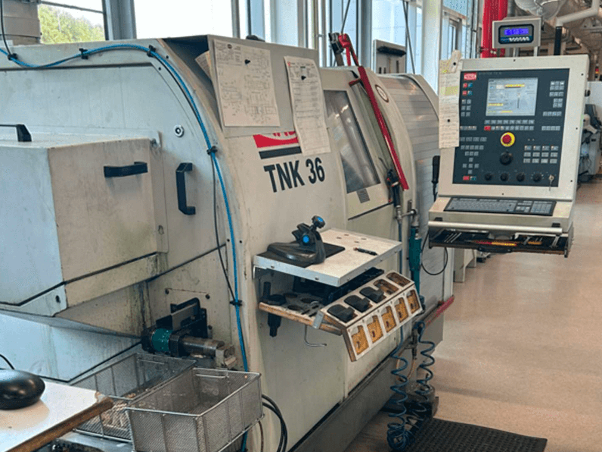 Horizontal view of TRAUB TNK 36 turning machine, featuring control panel, tool holder, and work area.