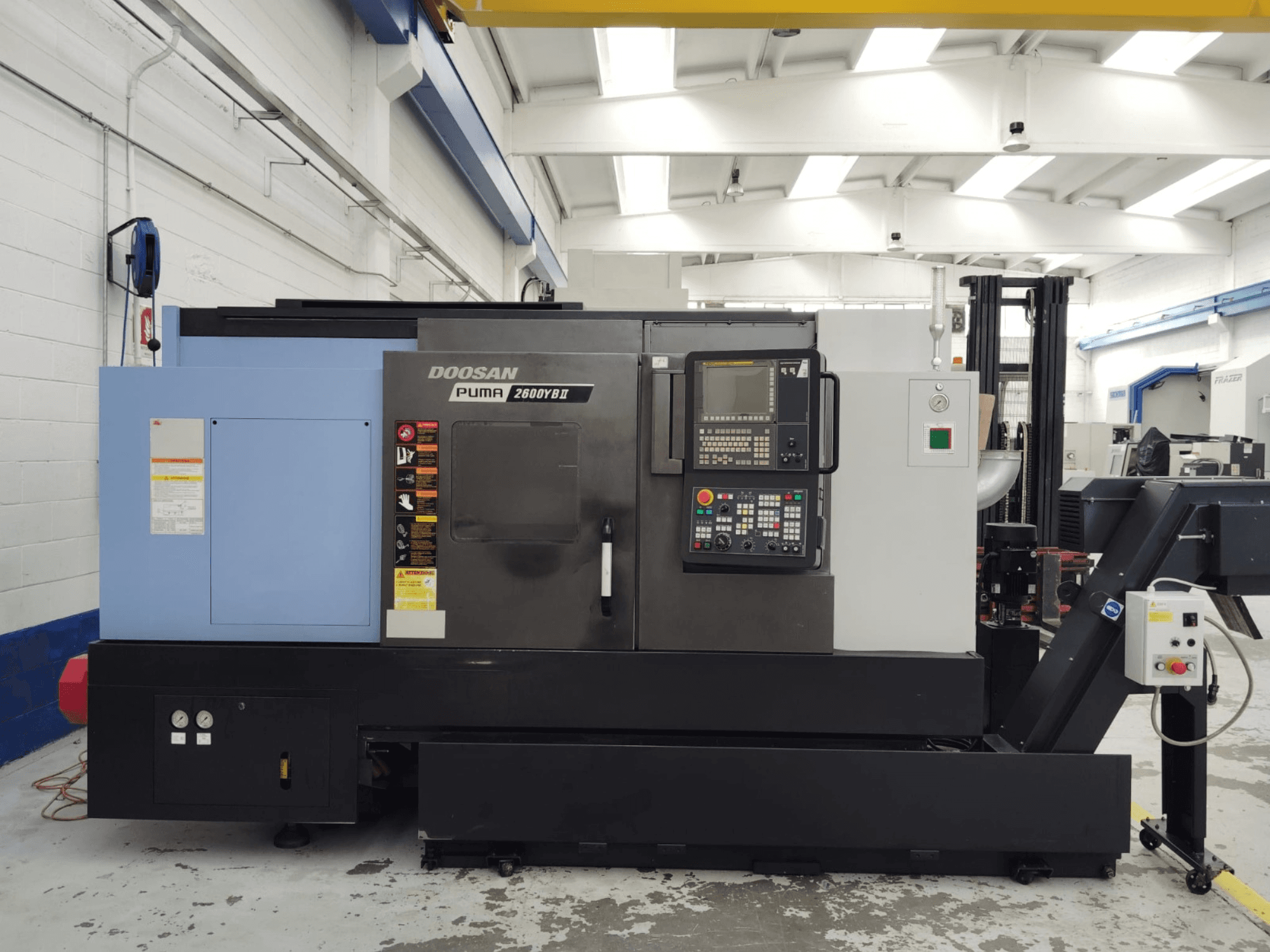 Front view of DOOSAN Puma 2600YB II horizontal turning machine with control panel and safety labels visible.