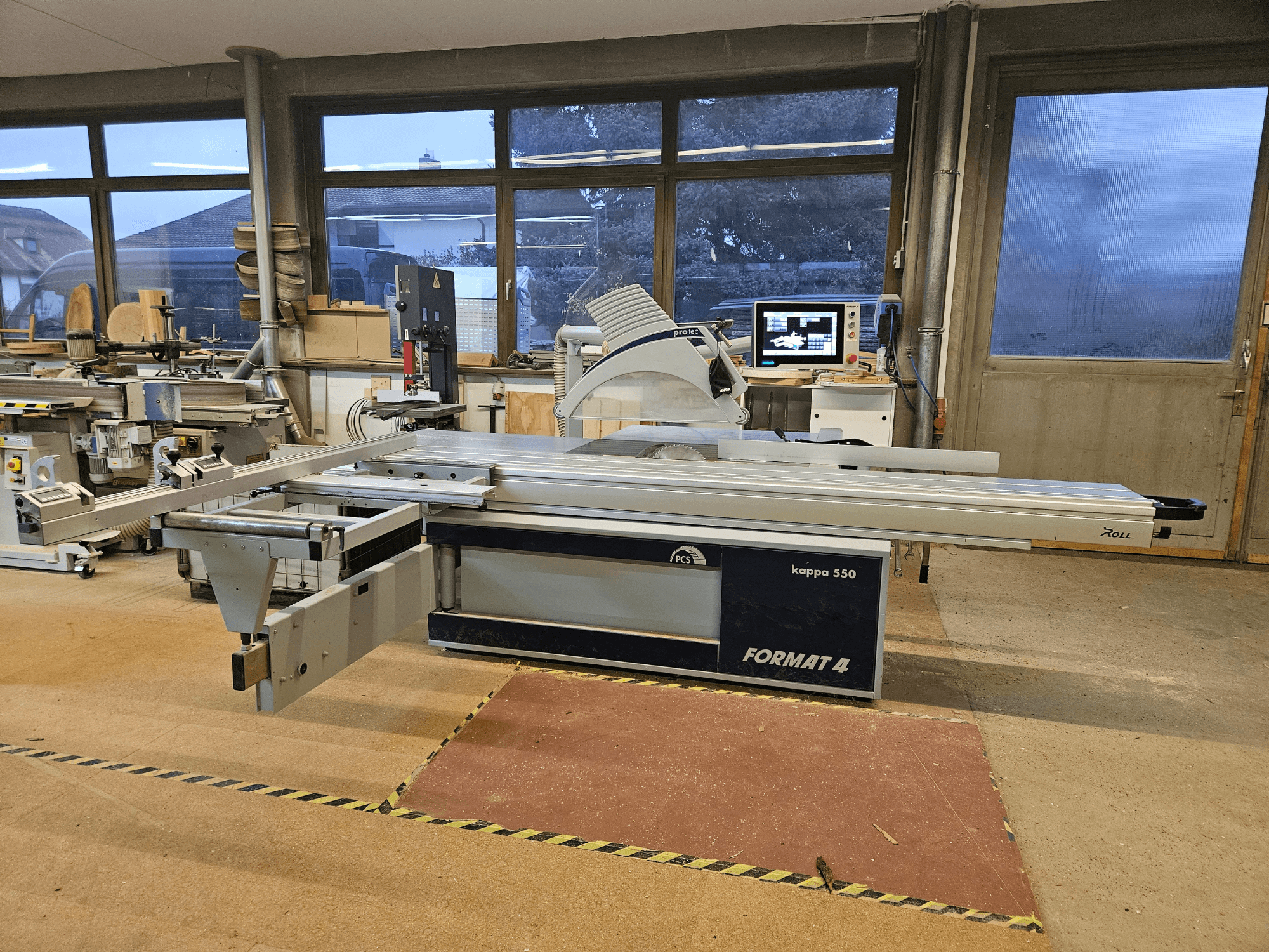 FORMAT4 kappa 550 woodcutting machine viewed from the side, showcasing extended sliding table and integrated monitor.