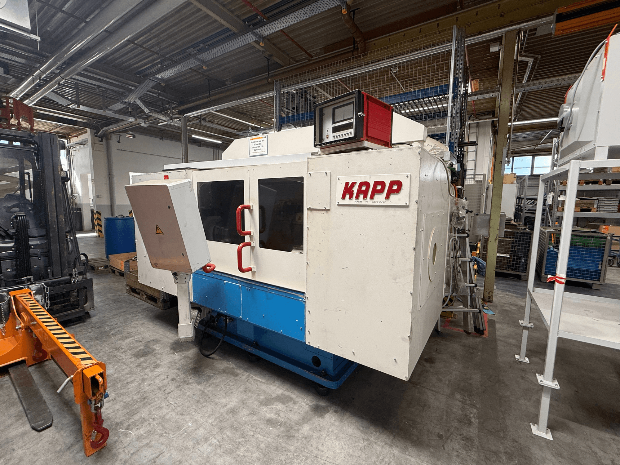 Cylindrical grinding machine KAPP RNS 55 shown from a side view, featuring control panel and safety enclosure in a workshop setting.