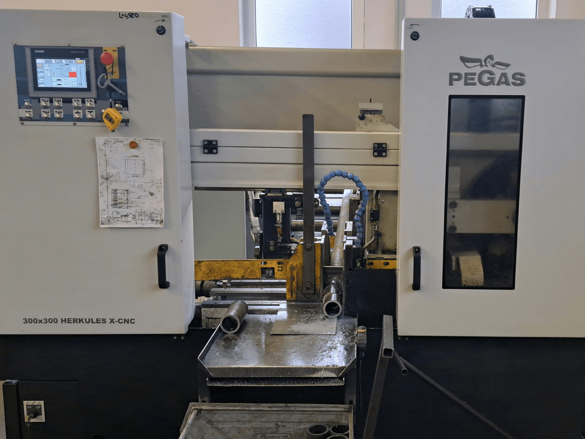 Pegas HERKULES X-CNC 300x300 sheet metal machine, front view, showing control panel and work area with metal pieces.