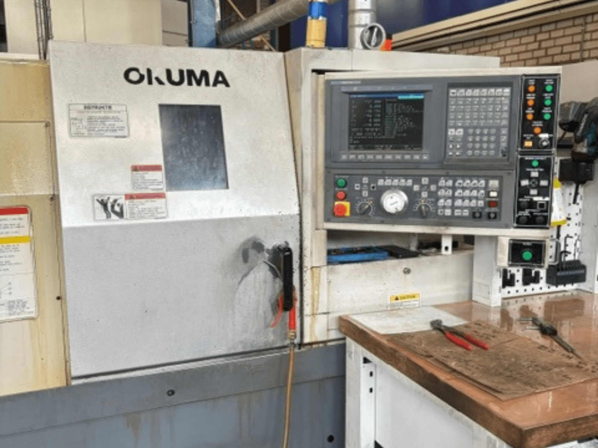 Okuma ES-L10II horizontal turning machine front view, featuring control panel, display, and workspace with tools.