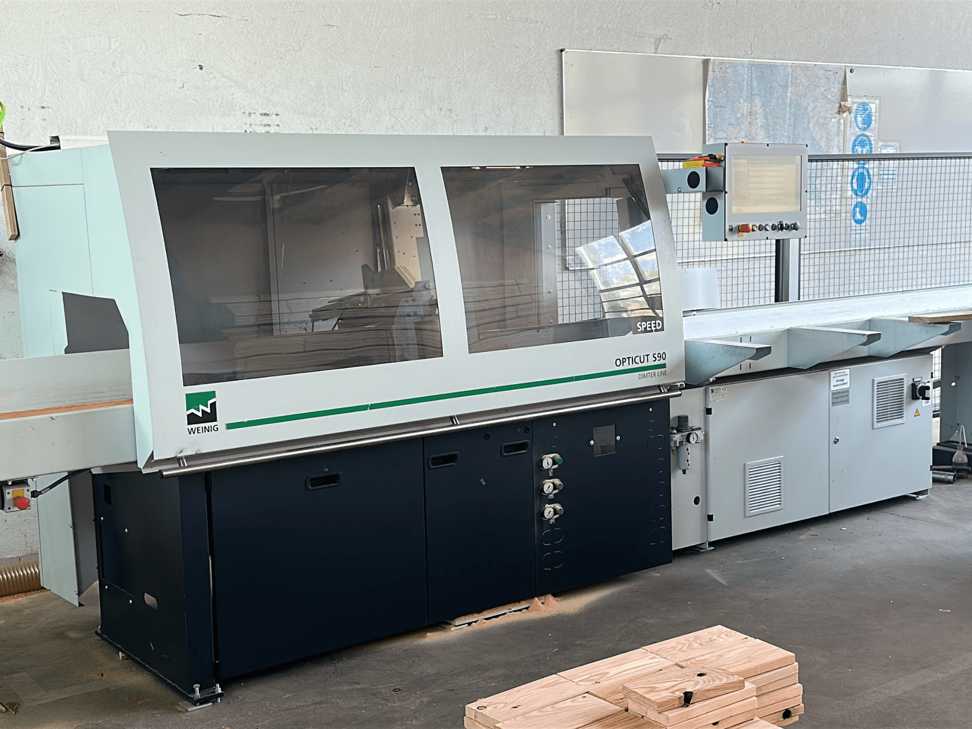 WEINIG Opticut S90 optimizing cross-cut saw in front view, featuring a clear safety enclosure and control panel.