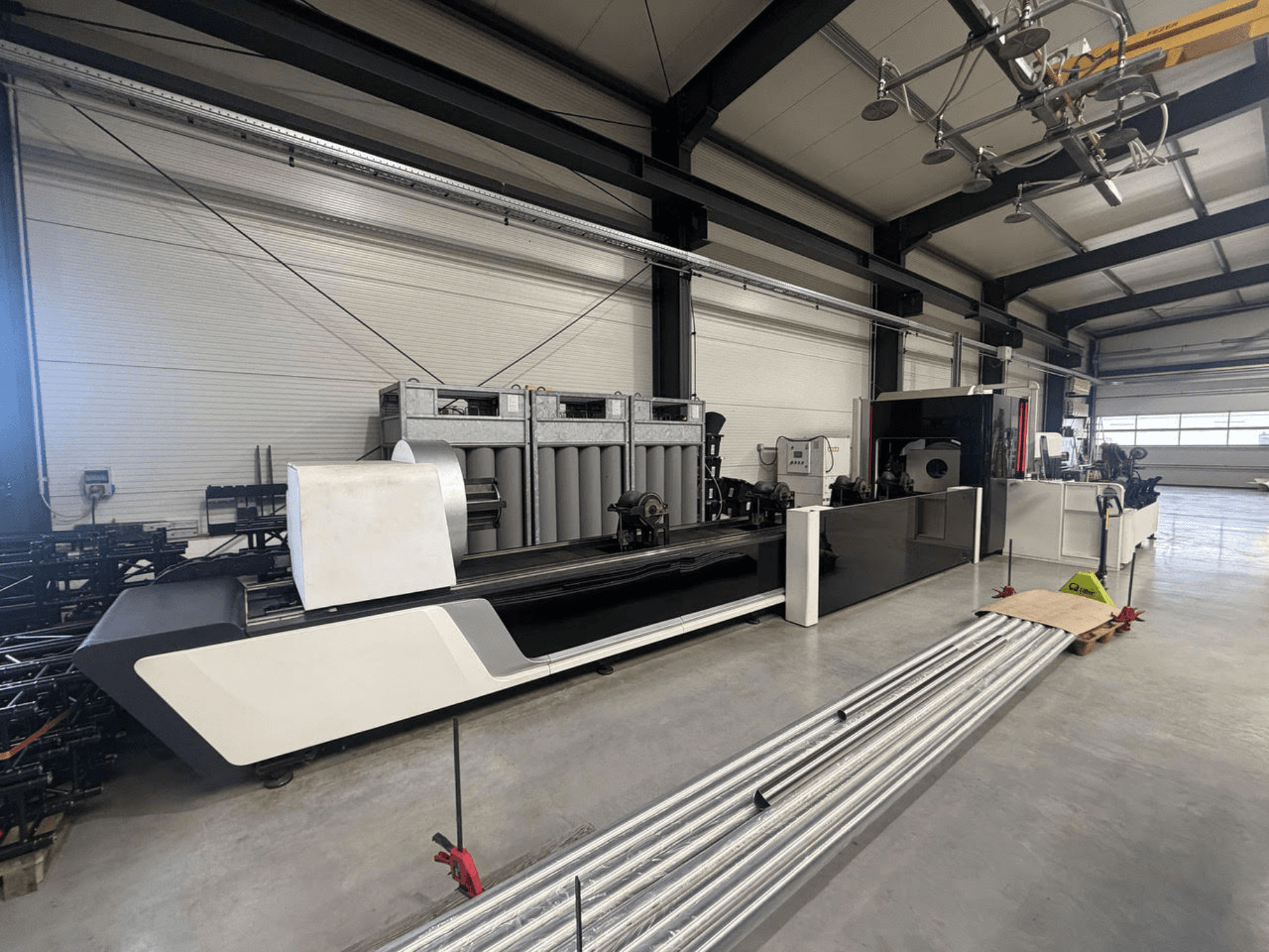 Bodor X2260 tube cutting machine in a workshop, side view showing machine body and metal tubes on the floor.