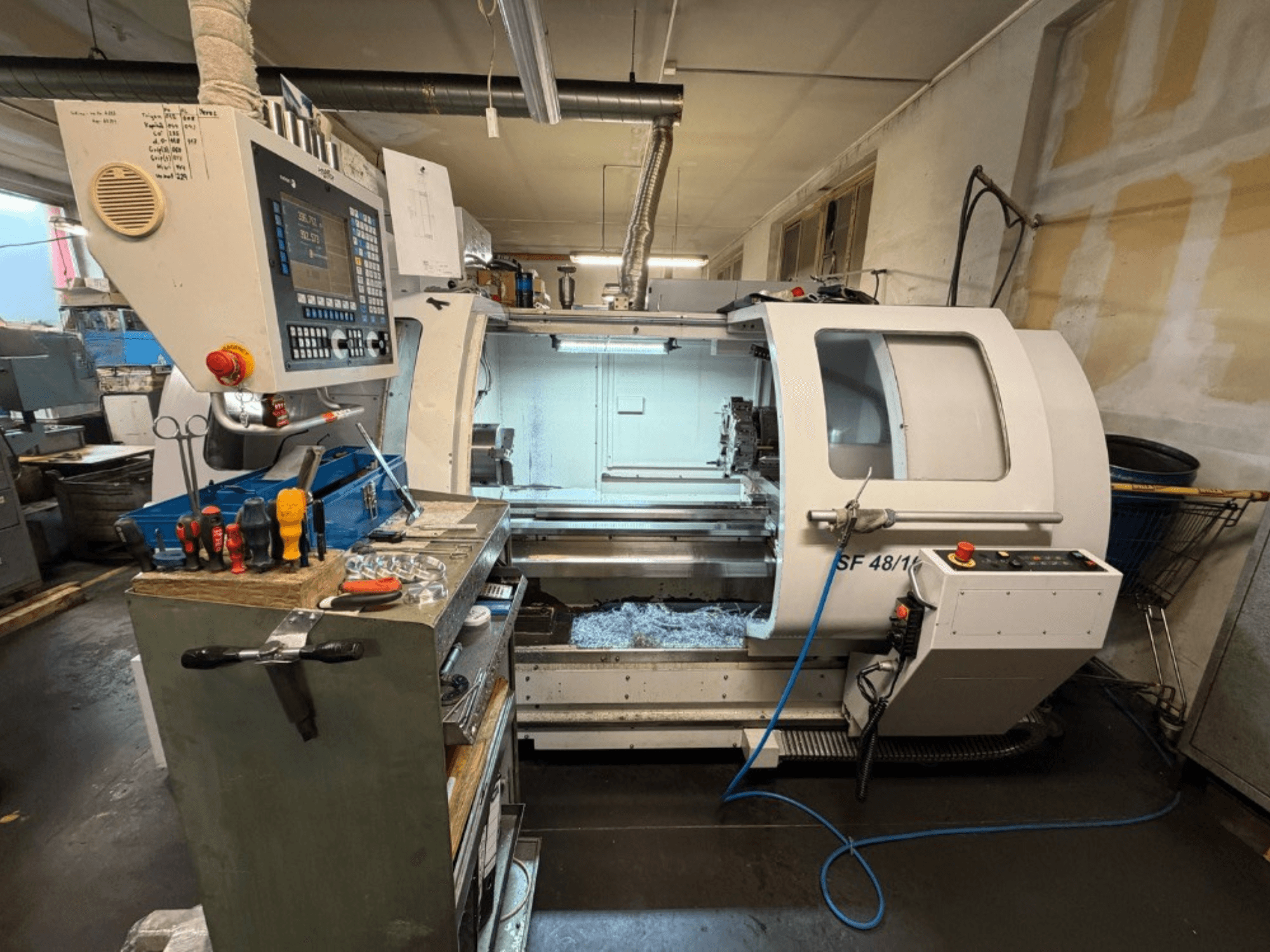 Horizontal turning machine MICROCUT SF 48/1000 viewed from the front, featuring a control panel and tools on the workbench.