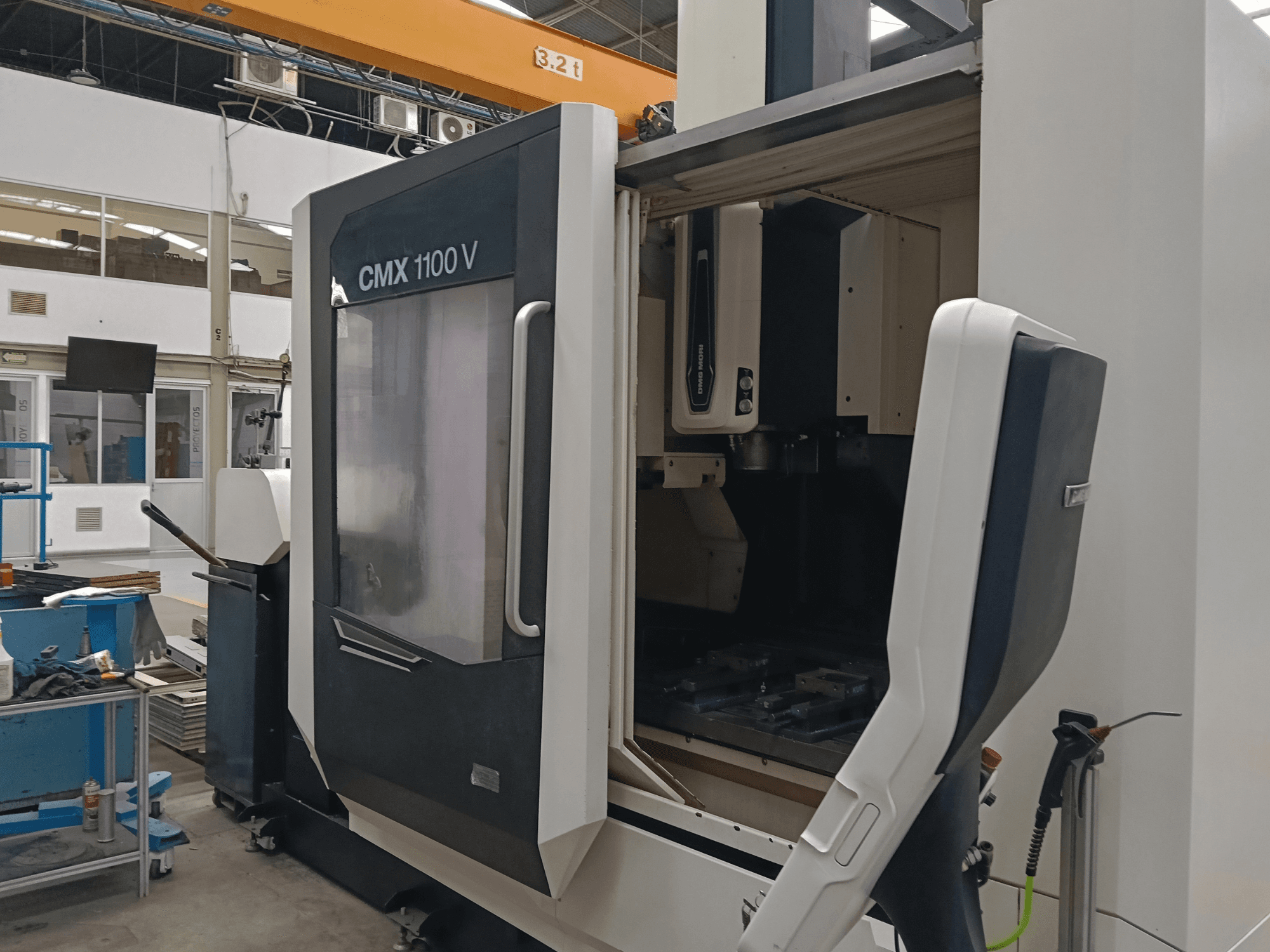 DMG MORI CMX 1100 V vertical machining centre, front view showing open door and interior tooling setup in an industrial space.