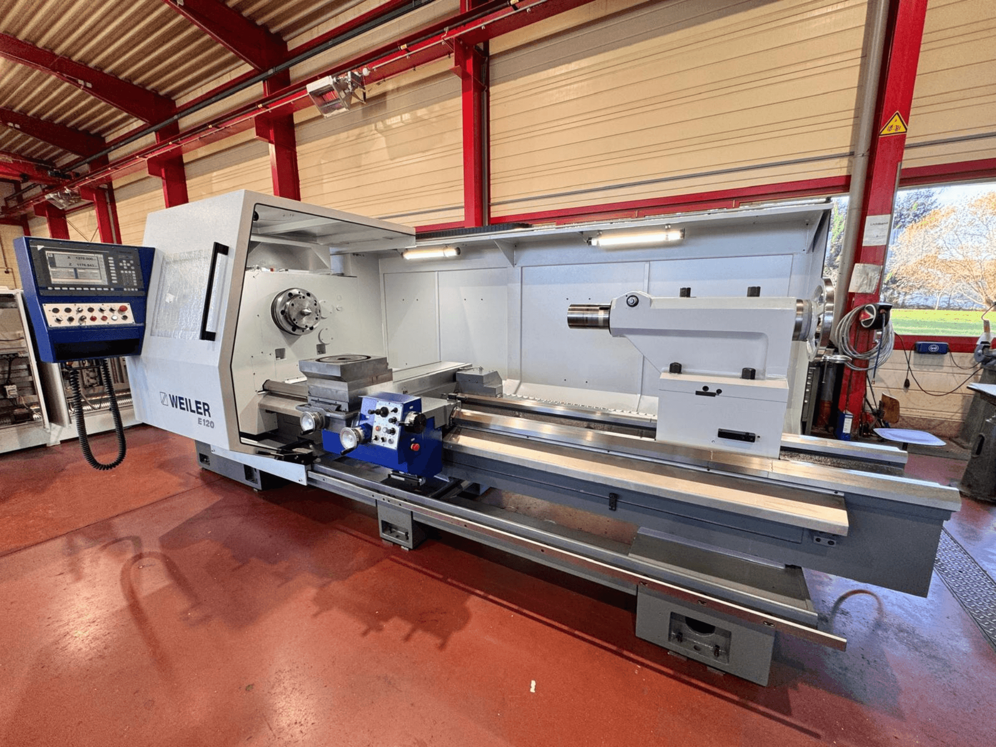 Weiler E120 lathe, front view, features a control panel, rotating spindle, and a precision bed with linear guides.