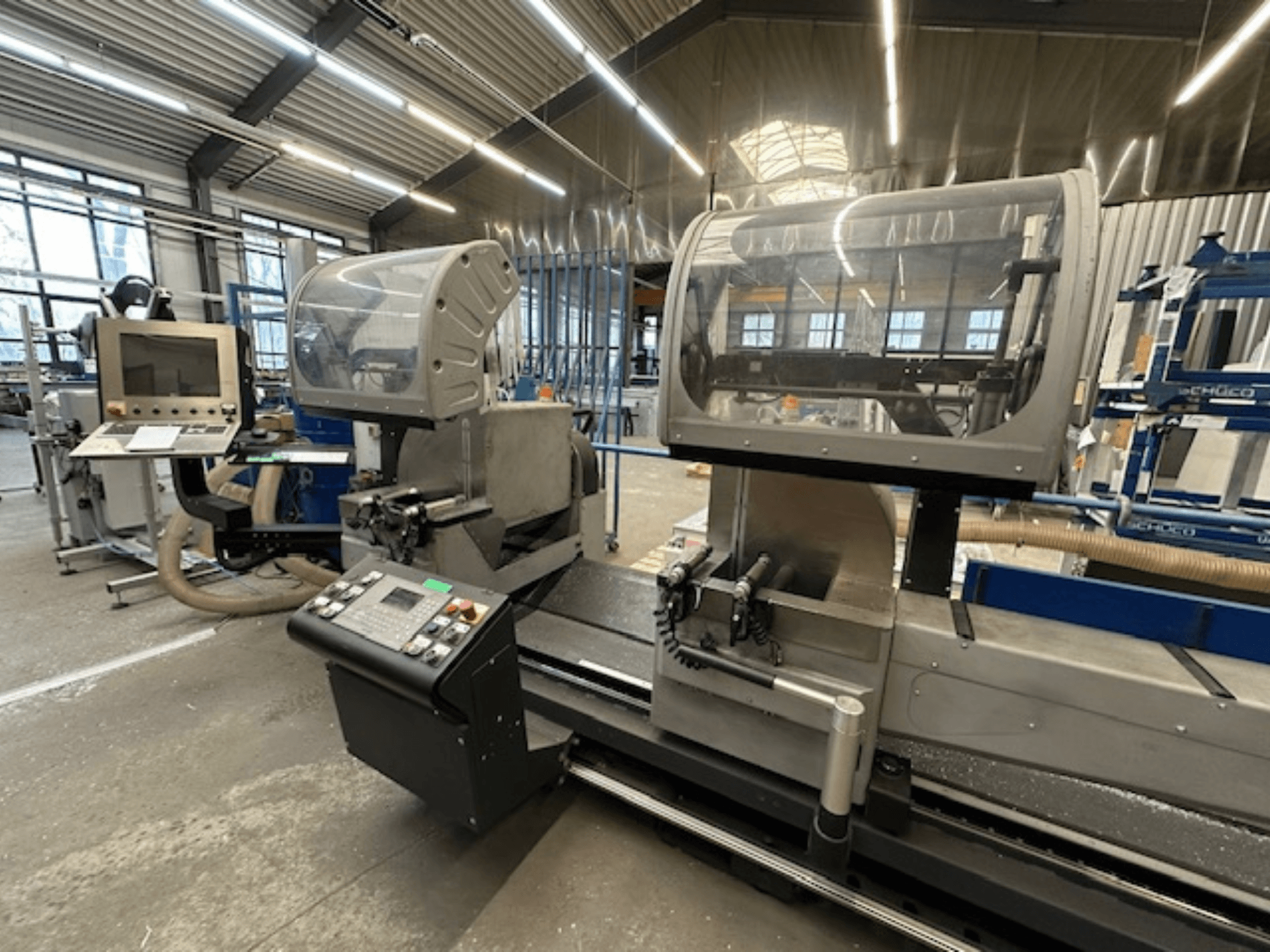 SCHÜCO PDG E CUT circular metal saw, front view, featuring control panel, protective covers, and cutting area in a workshop setting.