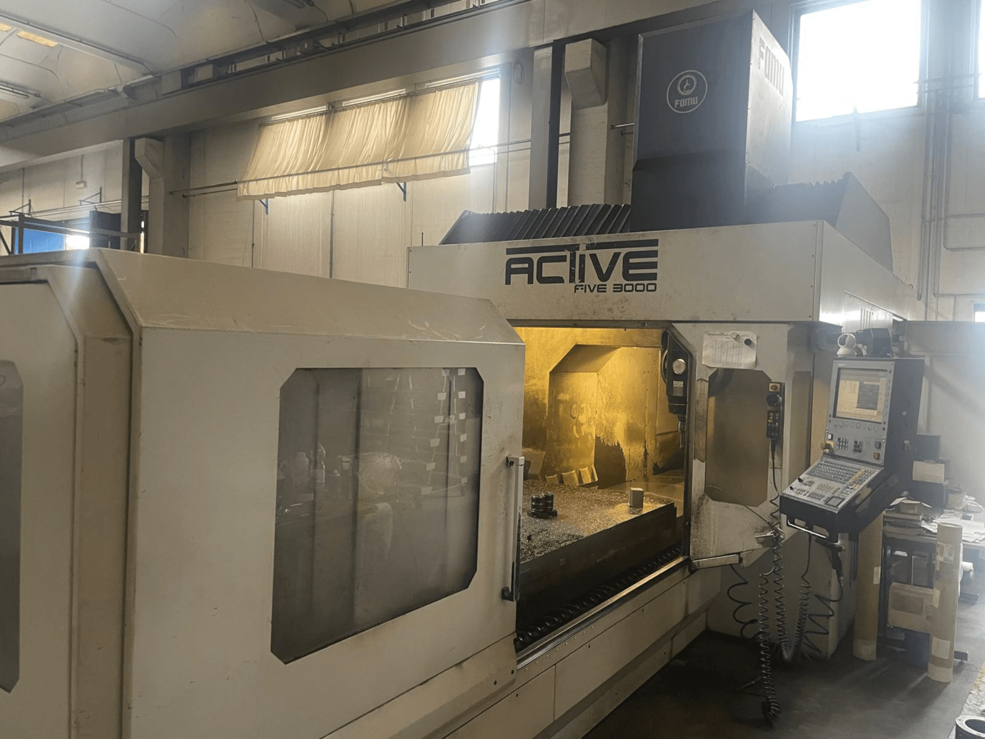 Front view of ACTIVE Five 3000 CNC machine, showing control panel and work area with partially machined part inside.