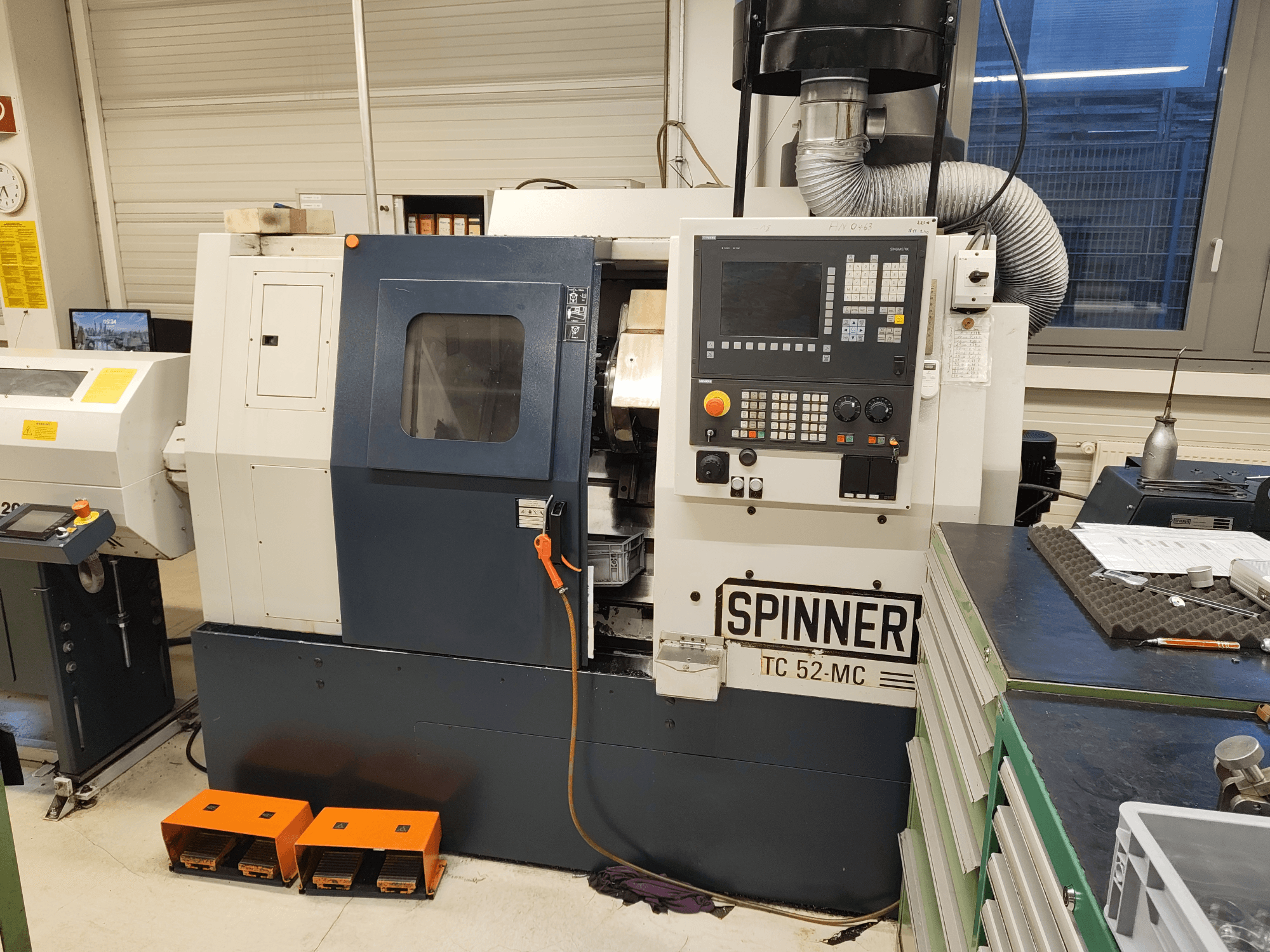 Horizontal turning machine SPINNER TC 52 MC in a workshop, front view, showing control panel, machining area, and safety features.