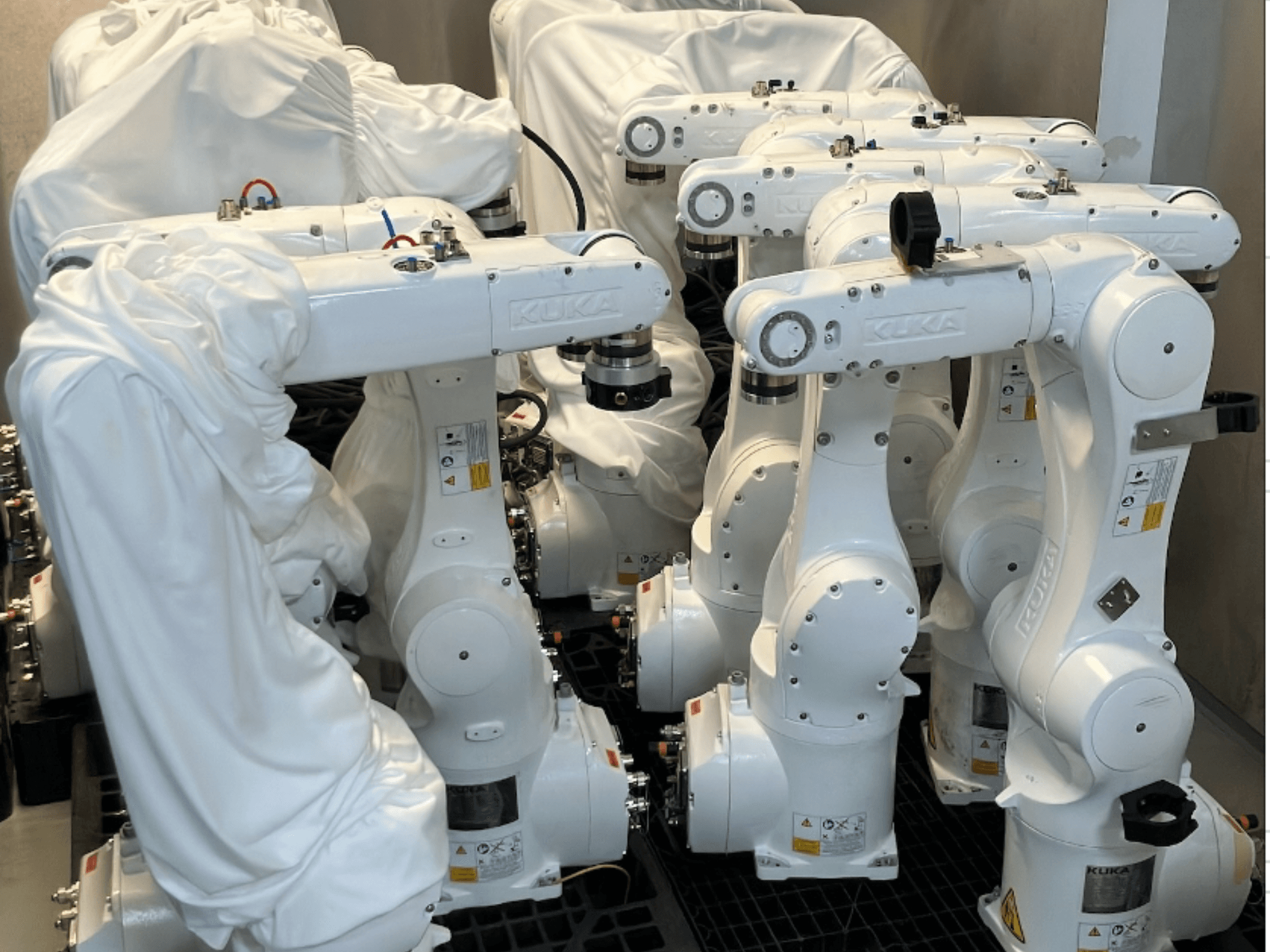 KUKA KR 10 R900-2 robot arms partially covered in fabric, viewed from the front, showcasing their sleek white design and technical details.