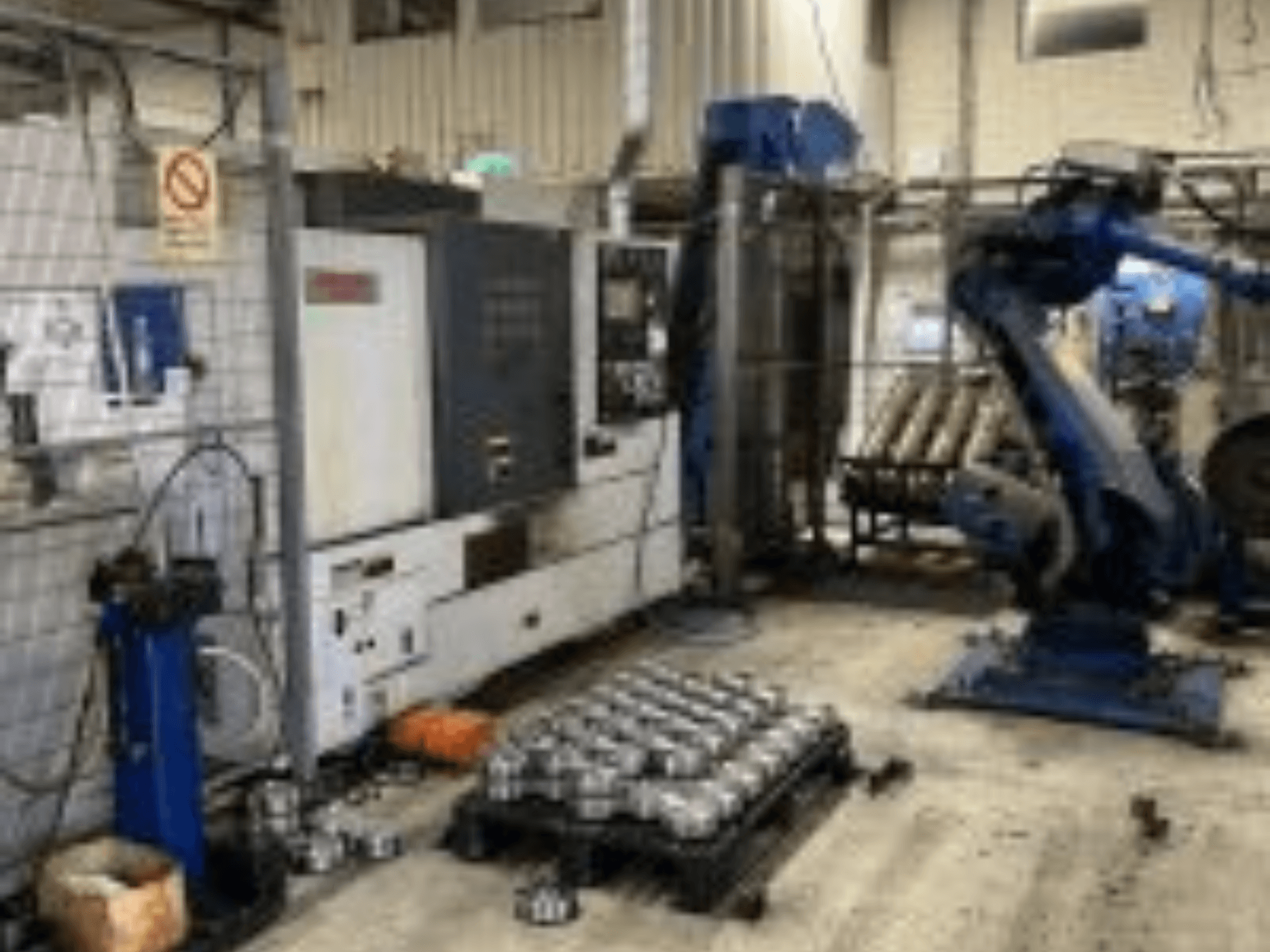 Horizontal view of MORI SEIKI NL 2500 MC/700 turning machine with robotic arm and metal parts on the floor.