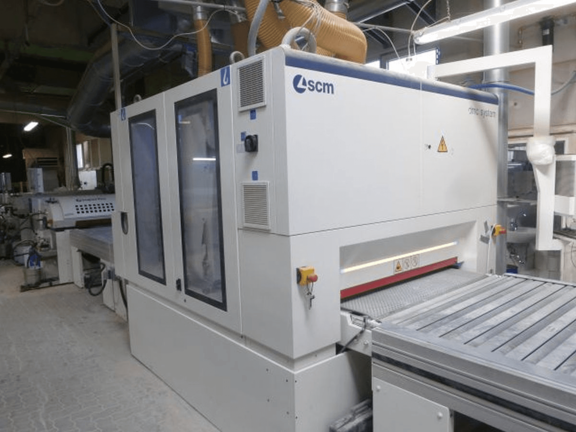 Belt sander SCM DMC SY TC 1350 in a workshop, side view showing control panel and sanding surface with safety features.