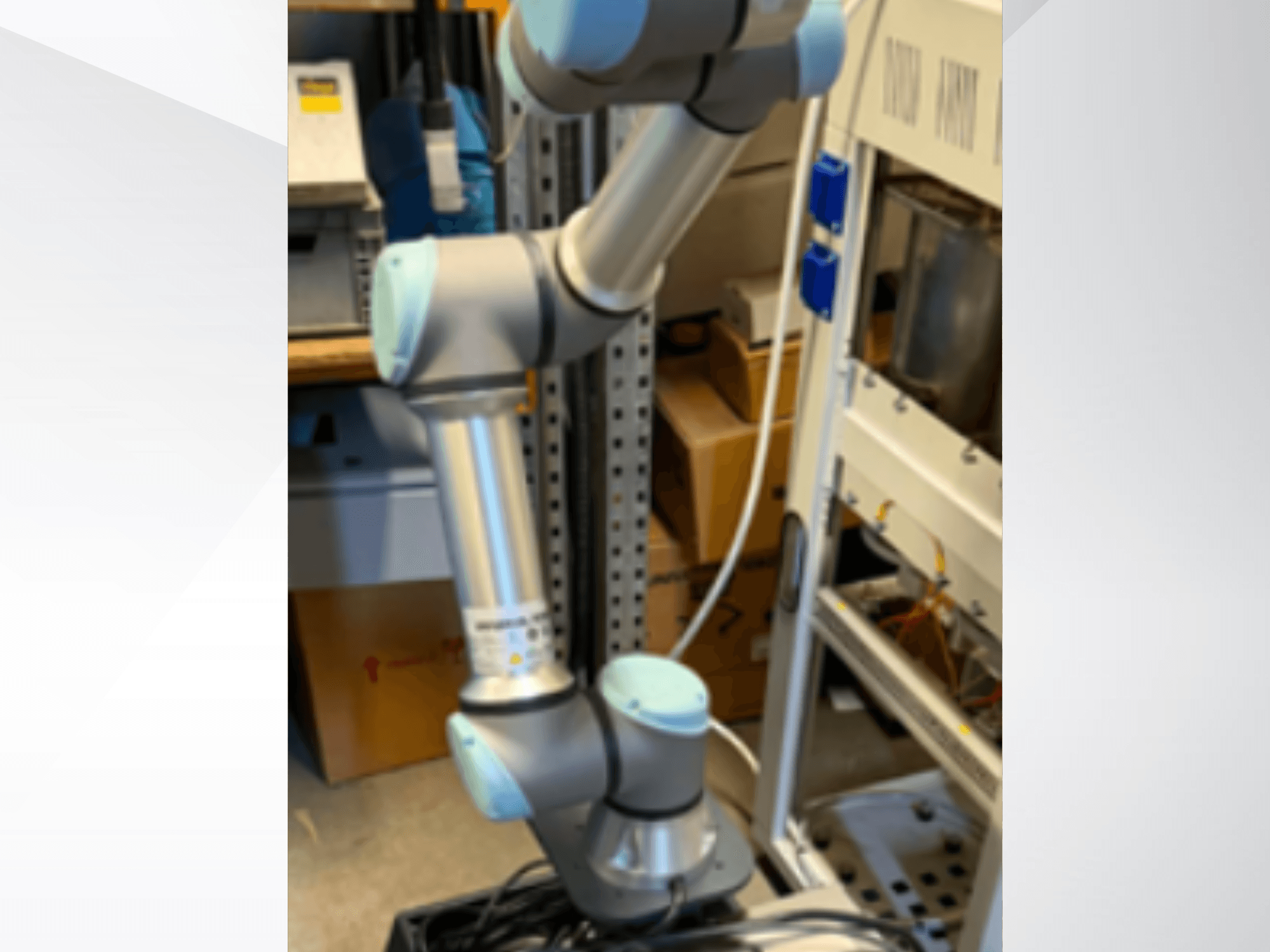 Universal Robots UR5e robot arm viewed from the side, displaying articulated joints, lightweight design, and control cables.
