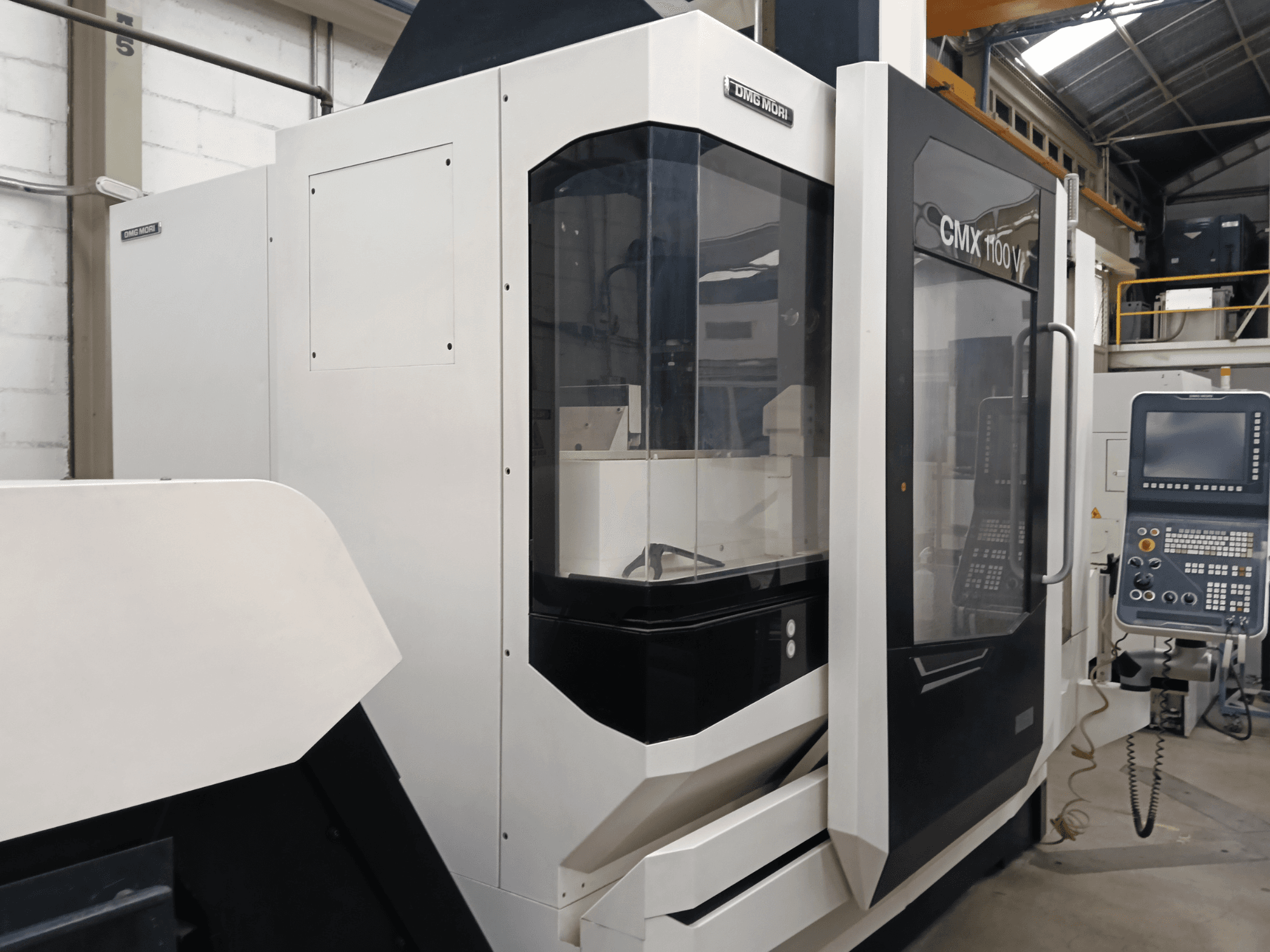 DMG MORI MORI CMX 1100 V vertical machining center, front view, showcasing control panel and glass enclosure.