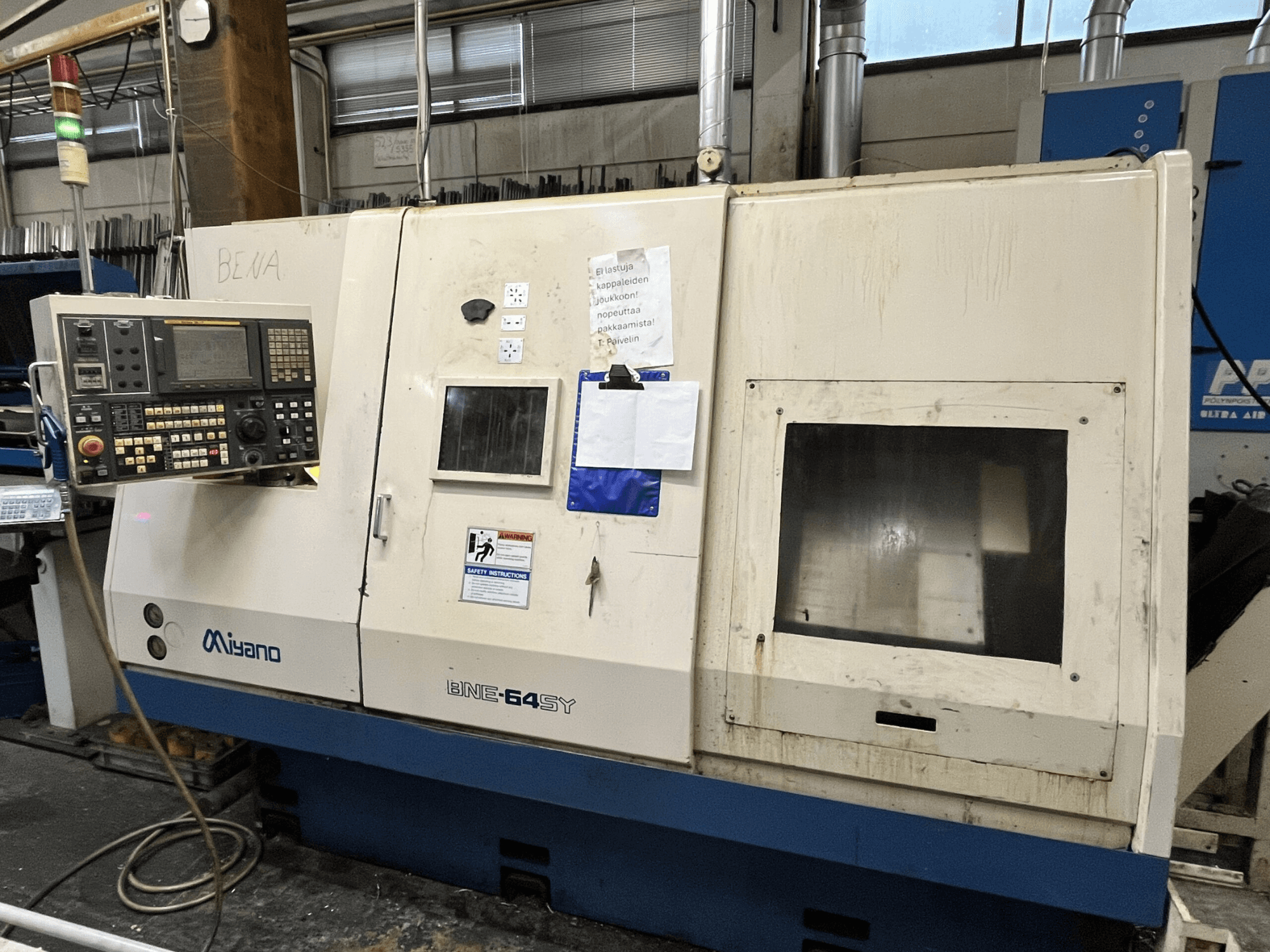 Miyano BNE-64SY CNC lathe machine, front view, features control panel with buttons, LCD, and maintenance stickers on the cabinet.