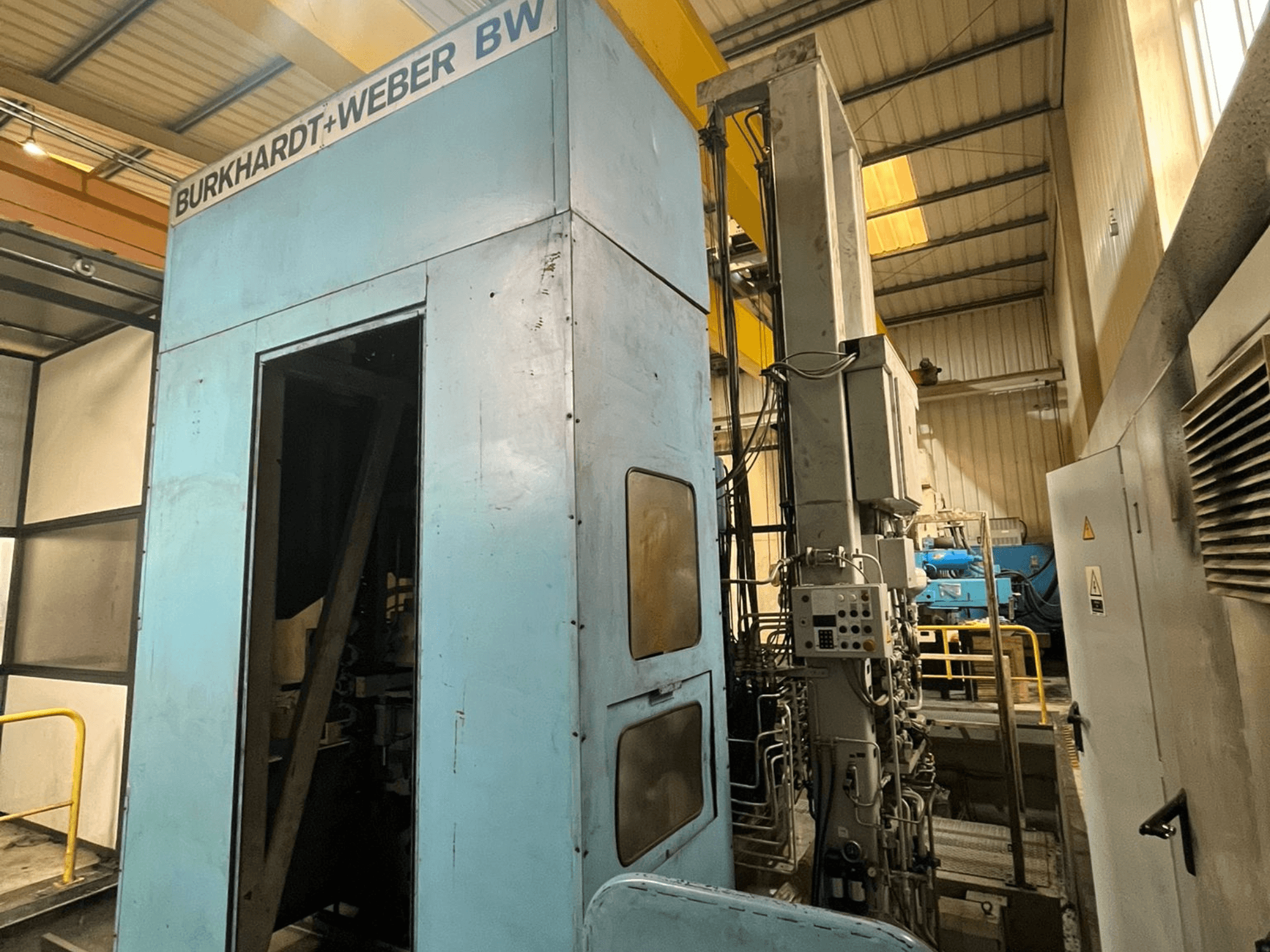 Burkhardt-Weber MC100 Horizontal Machining Centre, side view showing blue exterior and control panel with visible tubing.