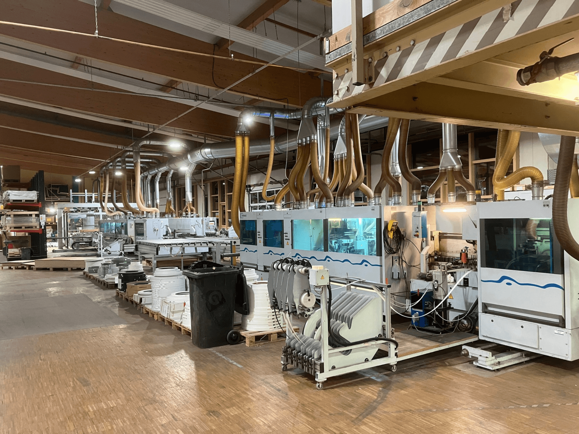 HOMAG KBZ KFR20 double-sided edgebander seen from a side view, equipped with ductwork and accessories in a workshop setting.