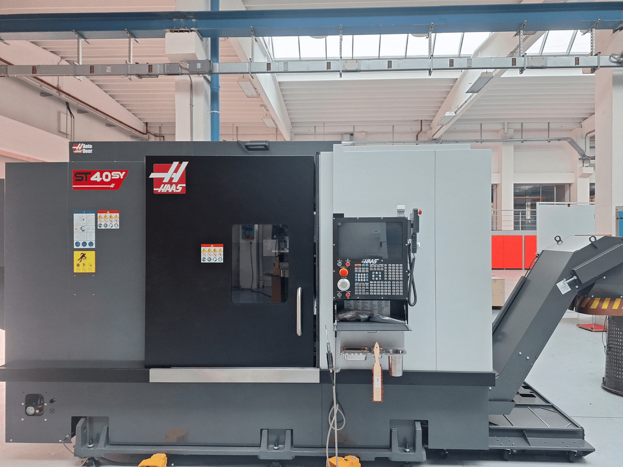 Haas ST-40SY horizontal turning machine in a side view, featuring a control panel and safety labels.