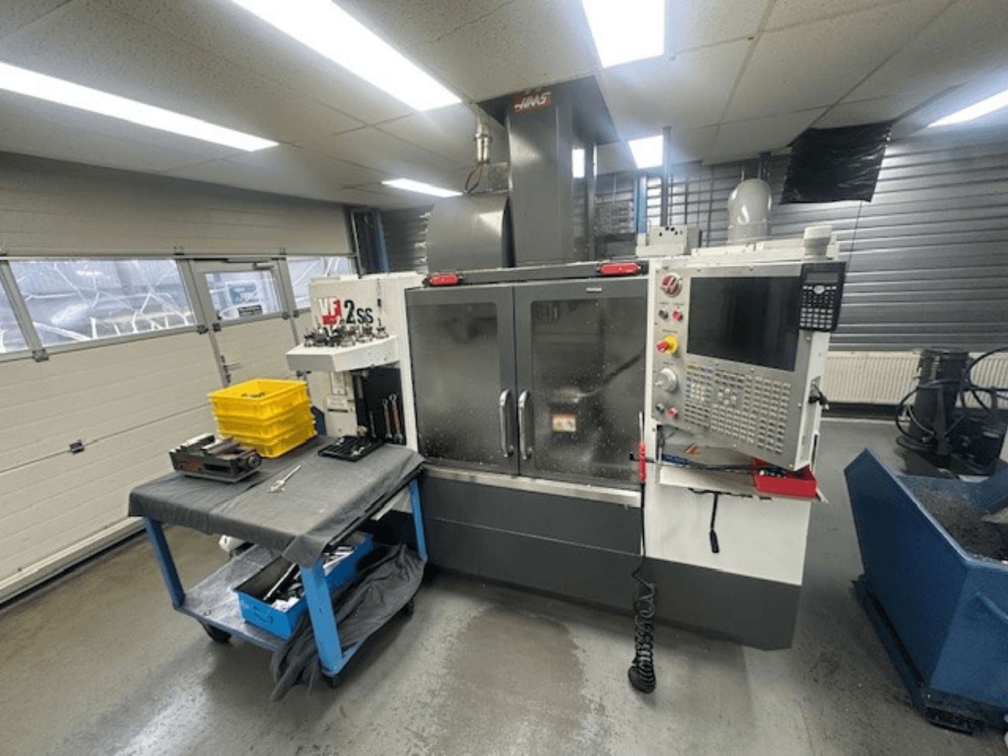 Front view of HAAS VF-2SS vertical machining center with control panel, worktable, and tool storage station.