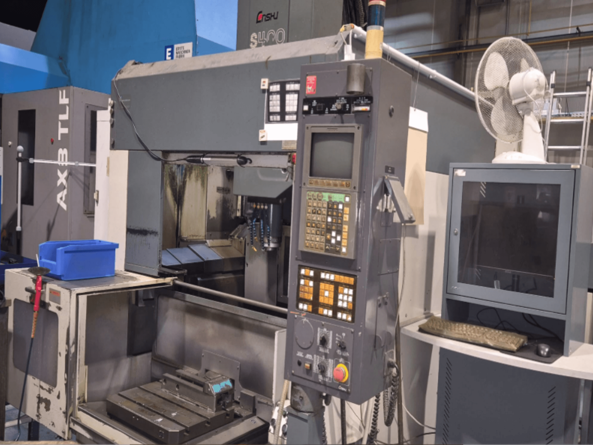 Vertical machining centre Enshu S400 in a workshop, showcasing control panel, monitor, and machine working area.