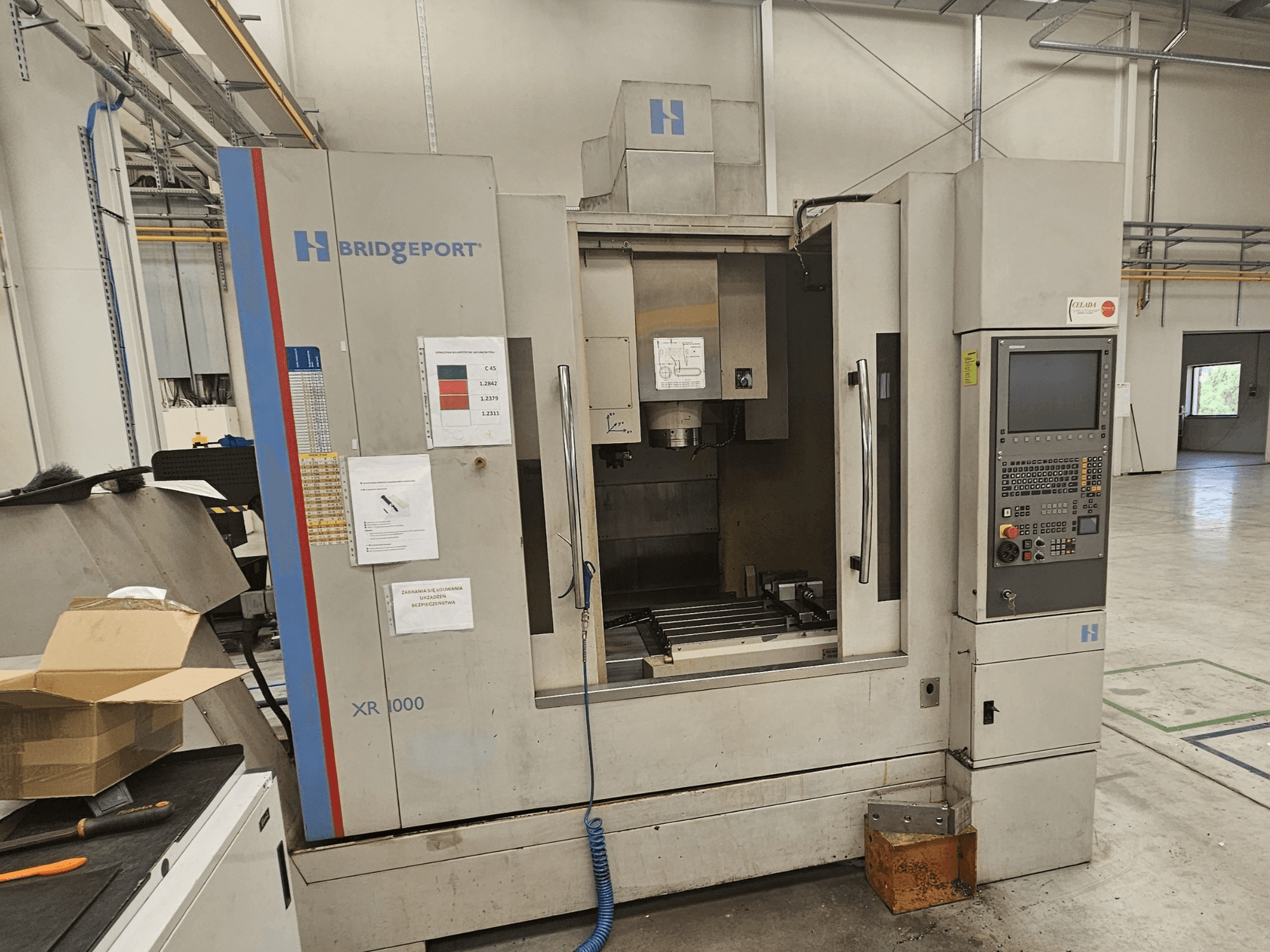 Bridgeport XR 1000 vertical machining center, front view, featuring a control panel and visible work area with a cutting table.