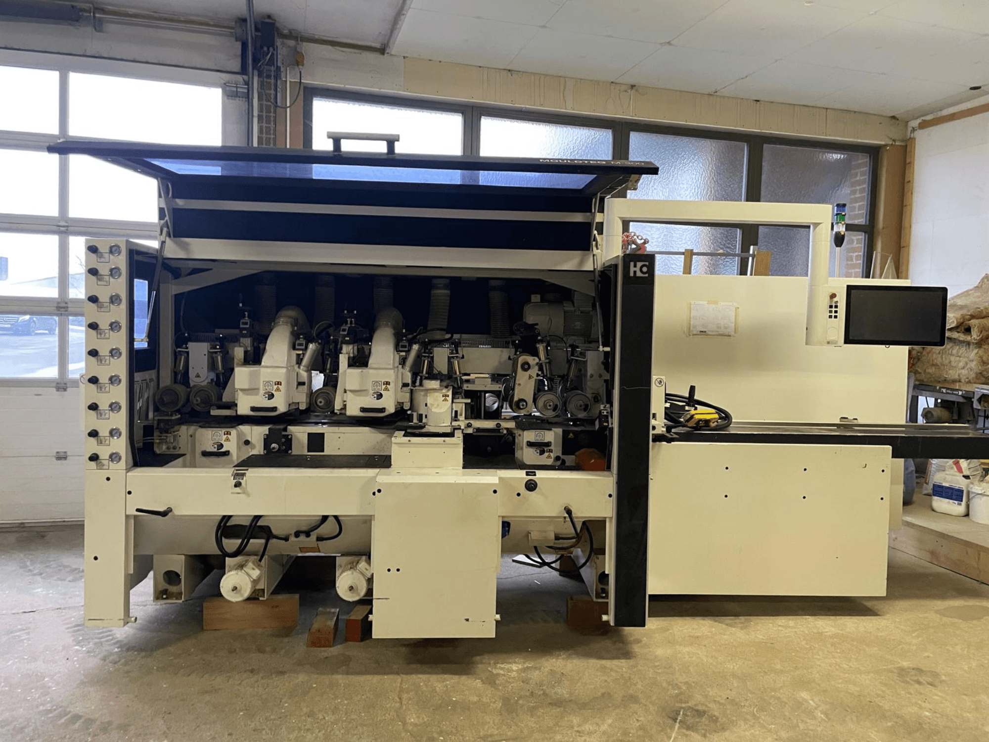 Häwa CNC machine, front view, features multiple spindles, control panel, and dust extraction hoses, suitable for wood processing.