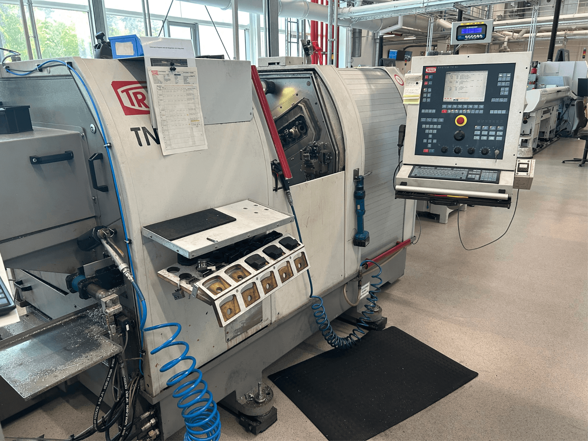 Horizontal turning machine TRAUB TNK 36, front view, showing control panel, tool holder, and work area with metal shavings.