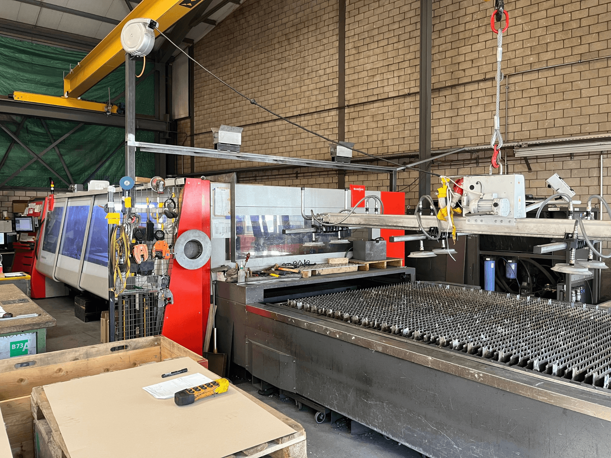 CO2 laser cutting machine Bystronic ByAutonom 4020, side view with work table, control panel, and overhead crane in background.