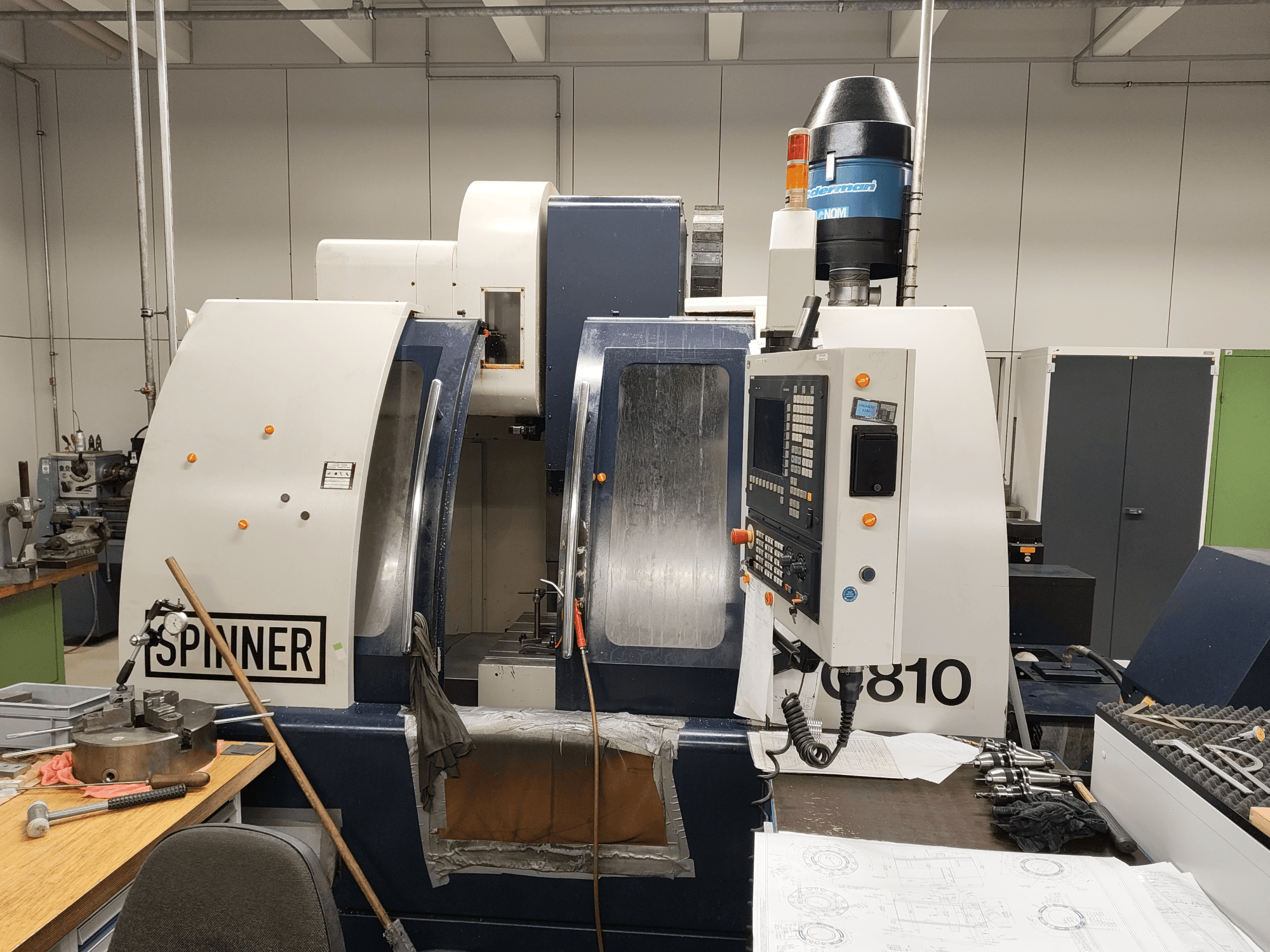 SPINNER VC810 vertical machining center, front view, showcasing control panel, workspace, and attached tools.