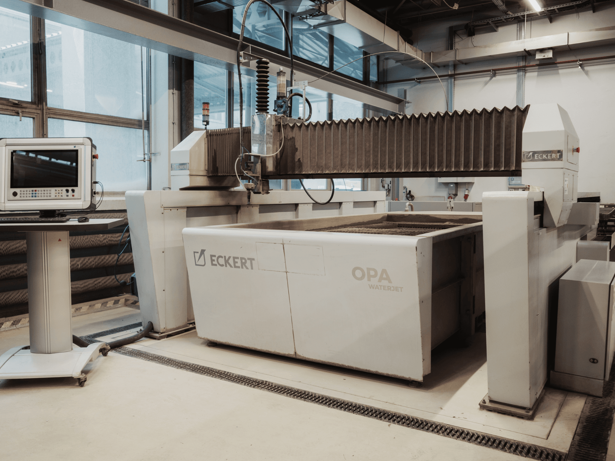 ECKERT OPAL WATERJET cutting machine in a workshop, shown from the front with control console nearby.