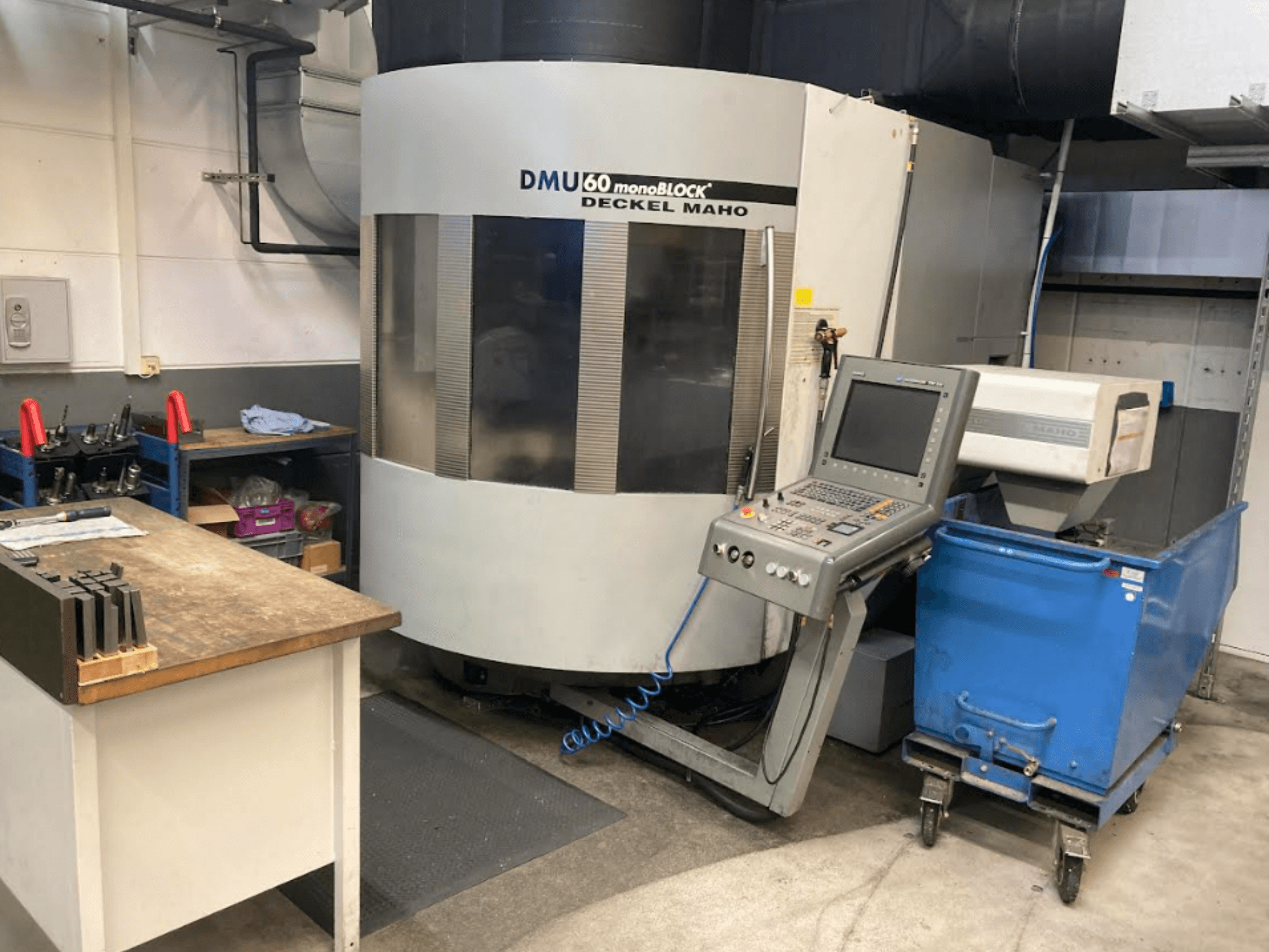 DMG MORI DMU 60 Monoblock vertical machining center, front view with control panel, workspace, and blue tool cart visible.
