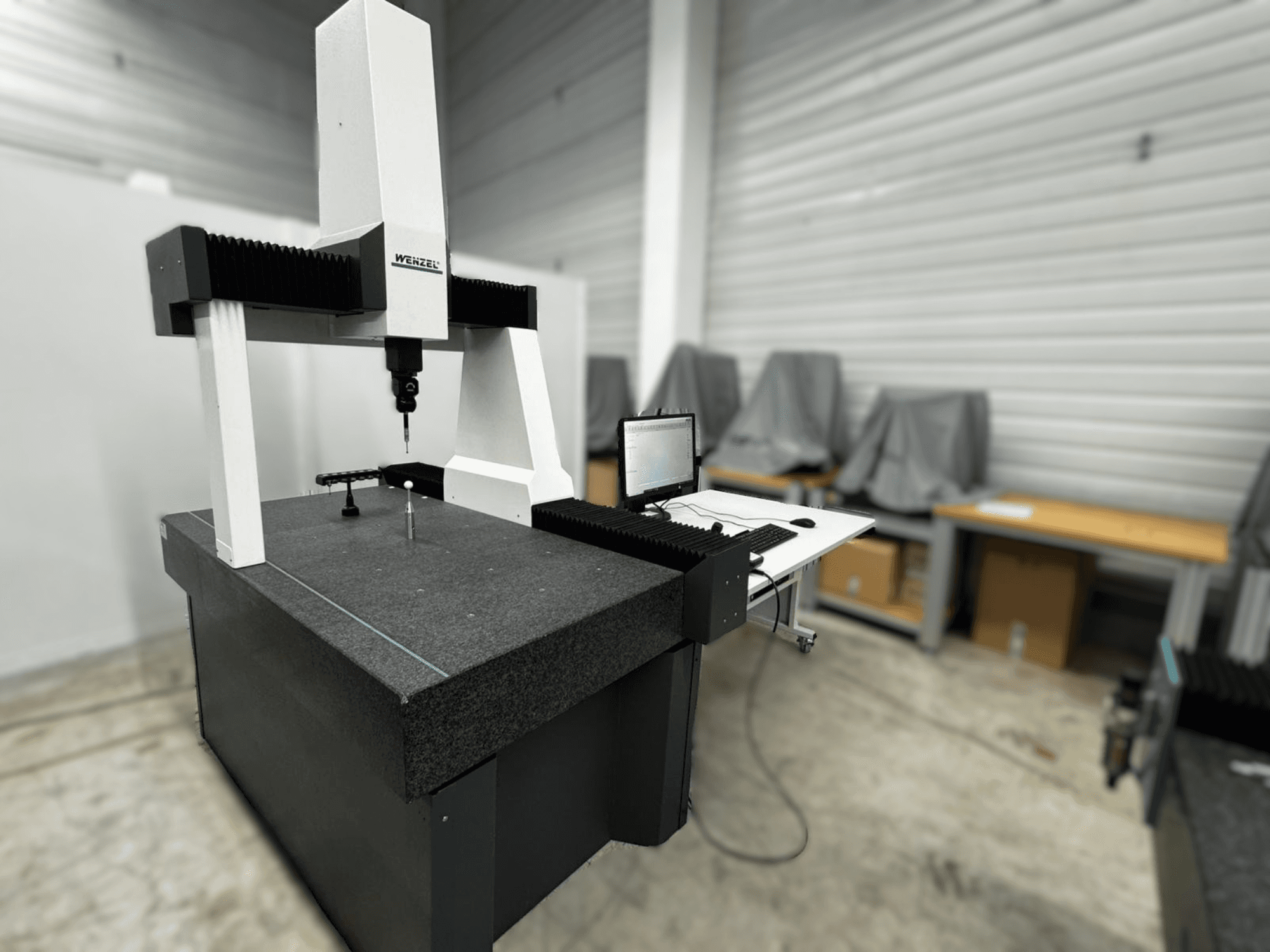 Wenzel LH 54 Coordinate Measuring Machine in a side view, featuring a probe and a computer interface on a gray base.