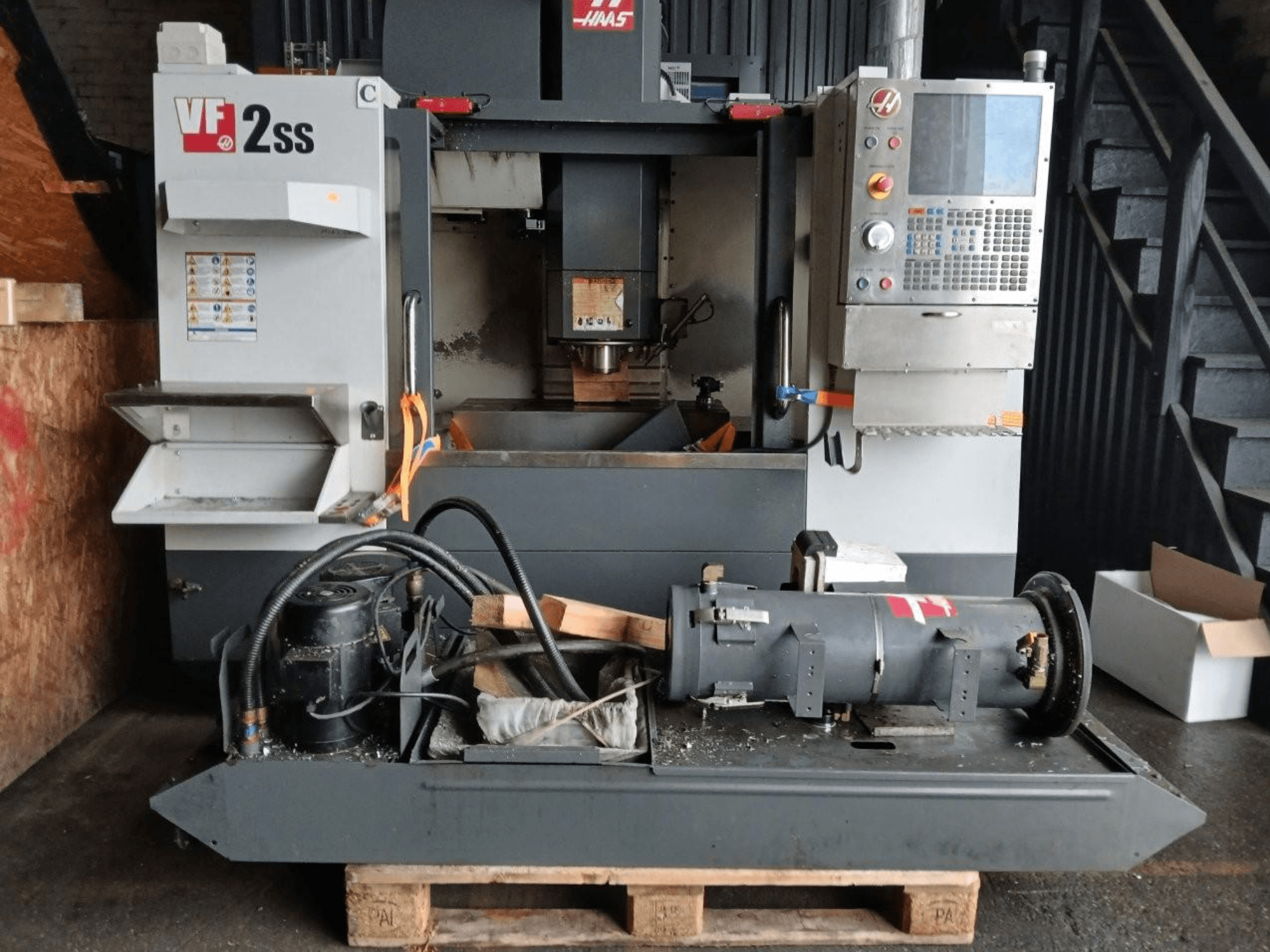 Vertical Machining Centre HAAS VF-2SS in front view, showcasing control panel, spindle area, and connected motor components.