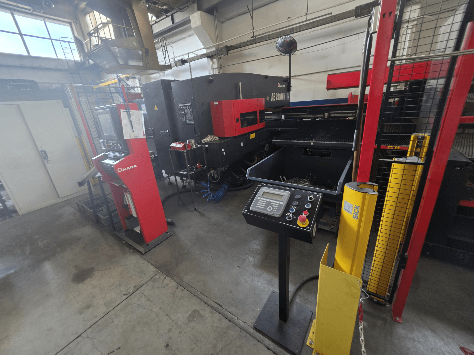 CNC Punching Machine AMADA AE-2510NT, front view with control panel, safety features, and surrounding industrial setting.