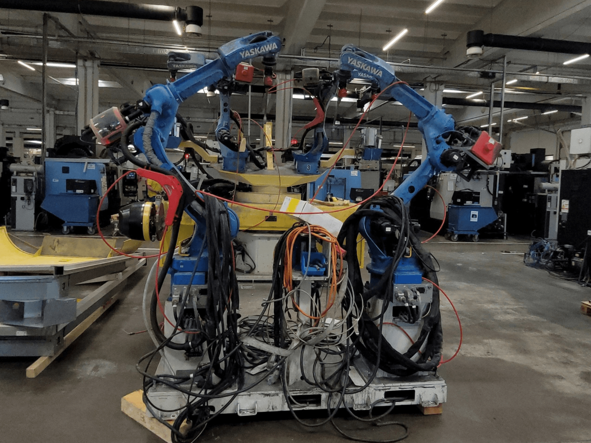 Yaskawa Robotic Welding Cell RWC L1_OS 15330, front view, featuring dual blue robots with extensive cables and welding tools.