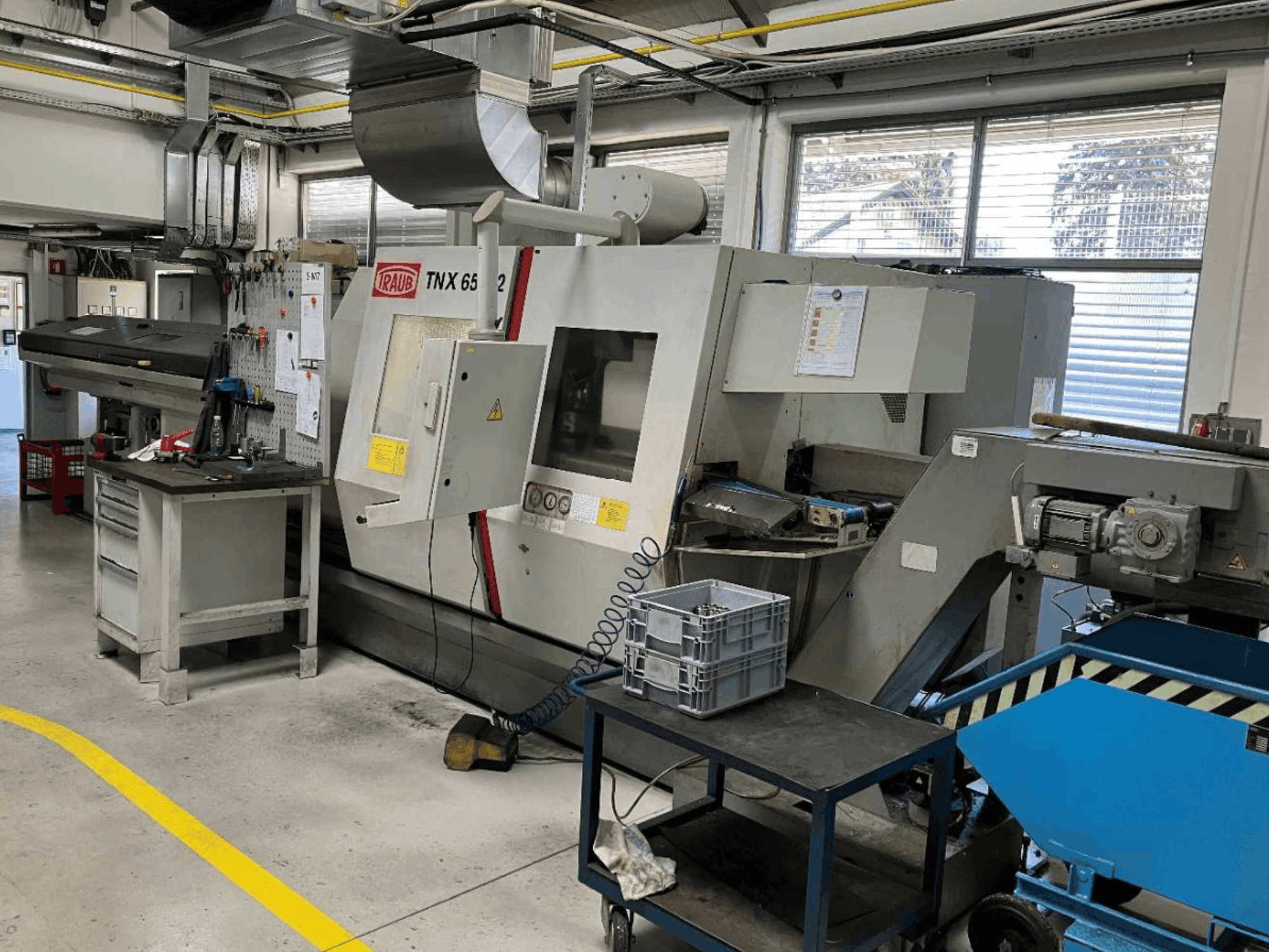 TRAUB TNX 65/42 Turn-Mill Centre in a workshop, front view showcasing control panel and workspace.