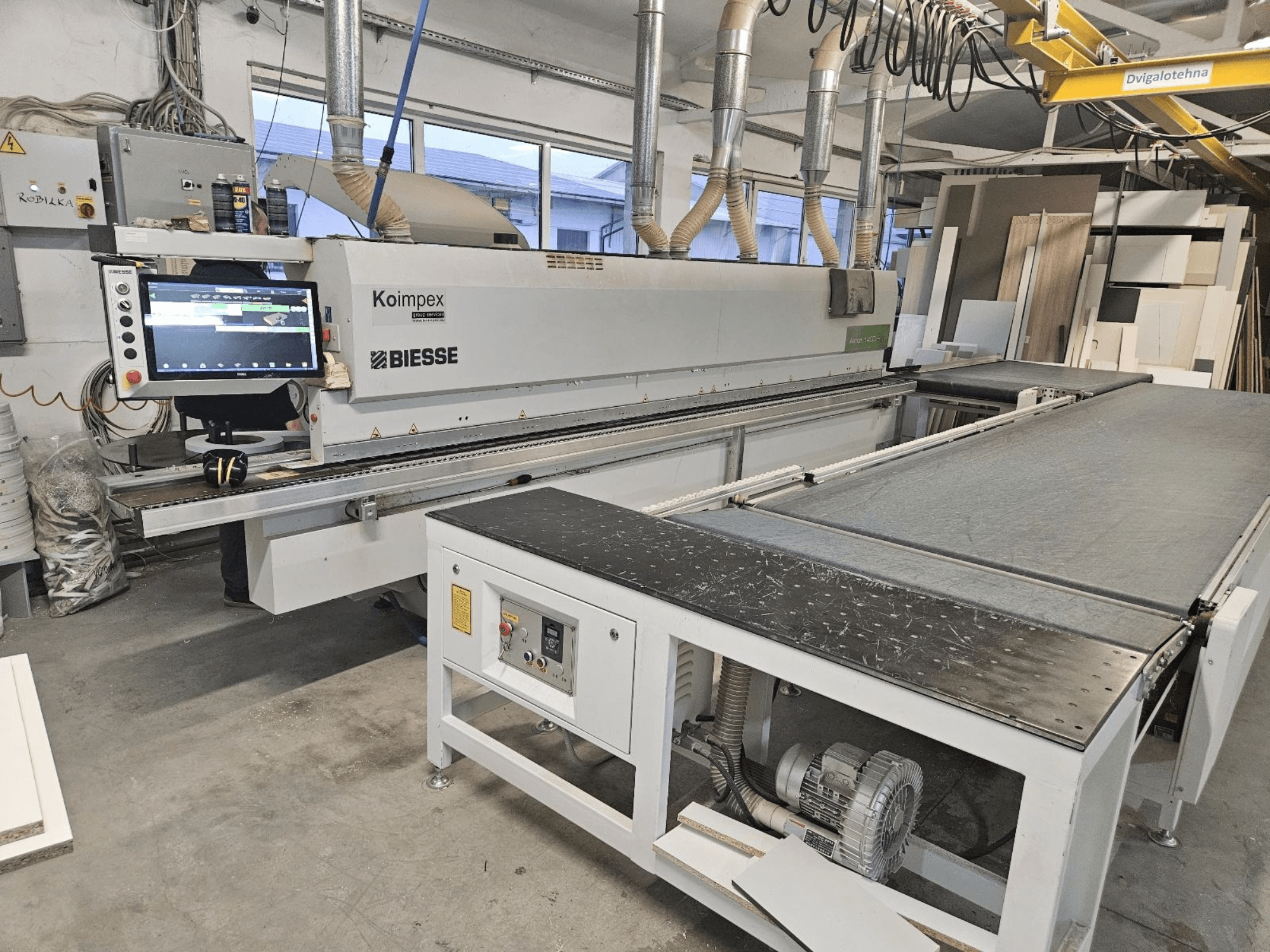 BIESSE Akron 1440 A edgebander in a workshop, side view showing control panel and conveyor belt.