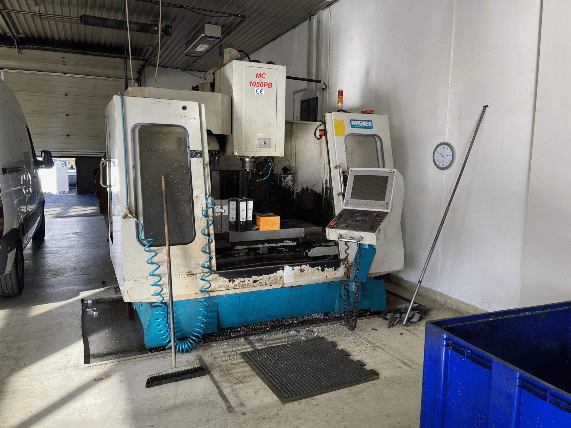 WAGNER MC 1050PB CNC machine in workshop, front view, with control panel and work area; blue air hose and cleaning tools visible.