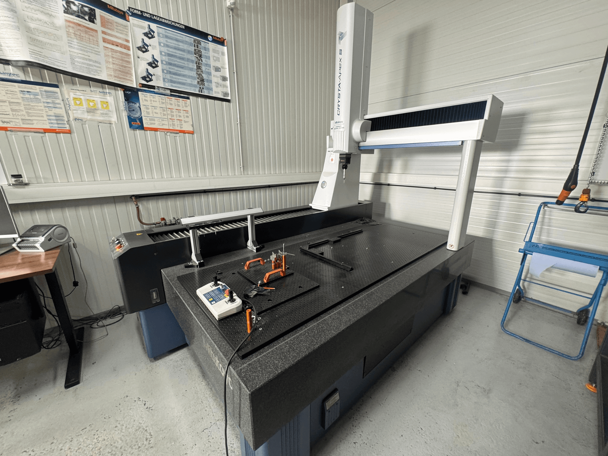 CMM coordinate measuring machine from the brand Leitz, front view on a textured black surface with measuring tools.